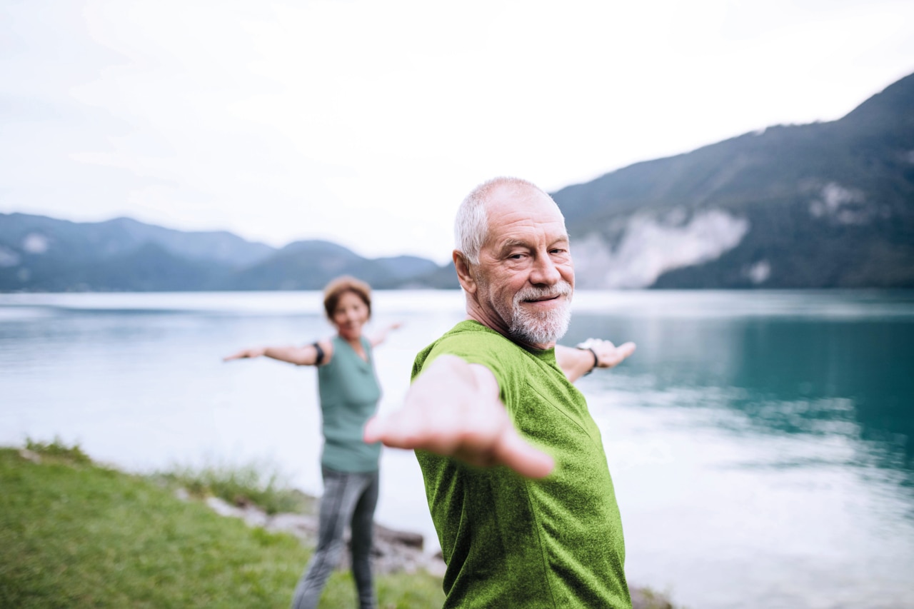 Middle aged couple exercising near a mountain lake