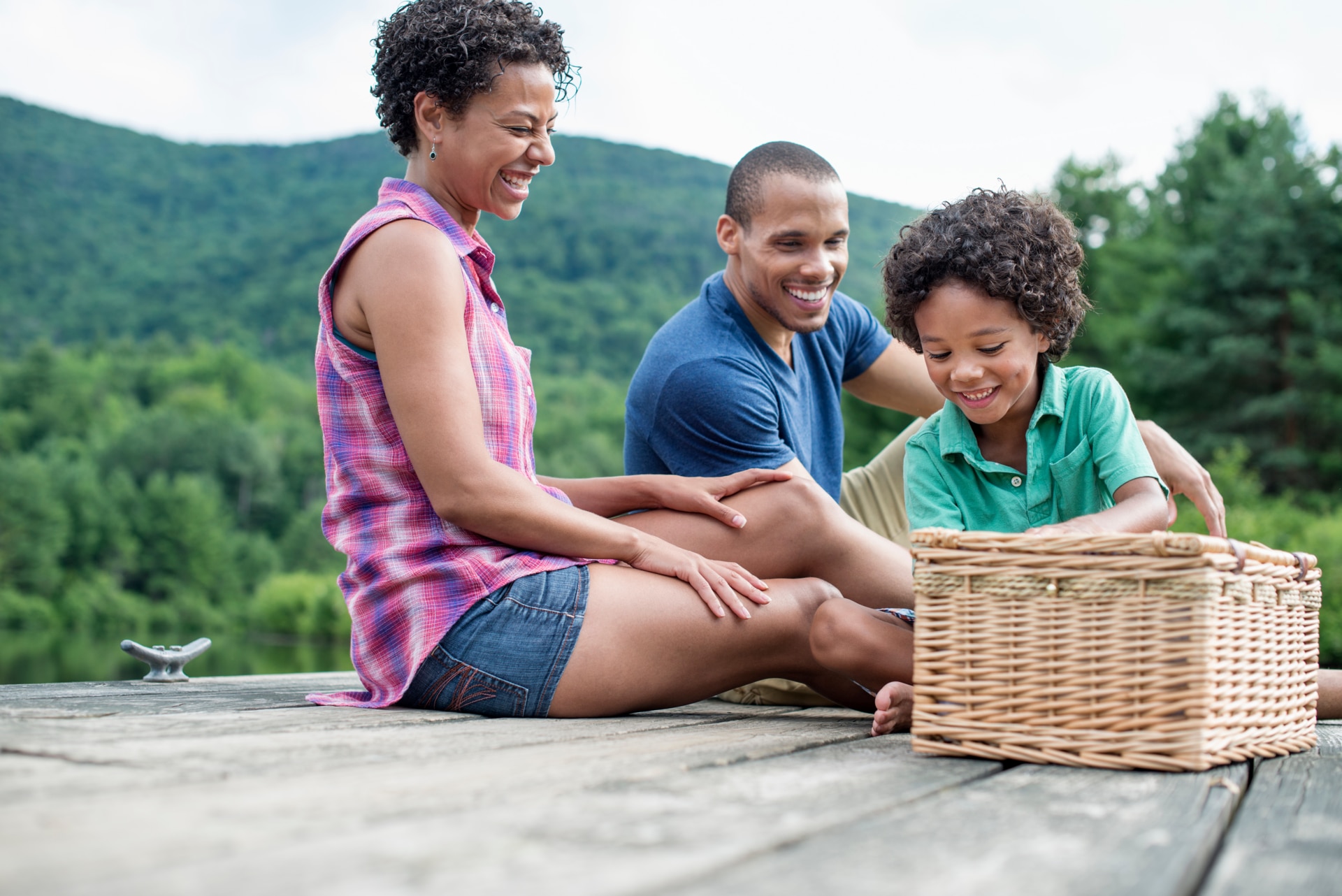 Famiglia di tre persone che fa un picnic estivo al lago.