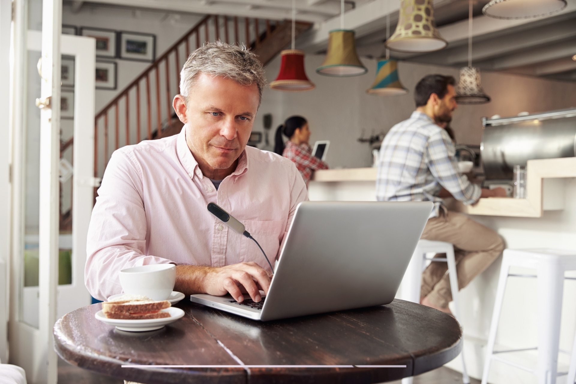 Mann mittleren Alters sitzt an einem Laptop im Café