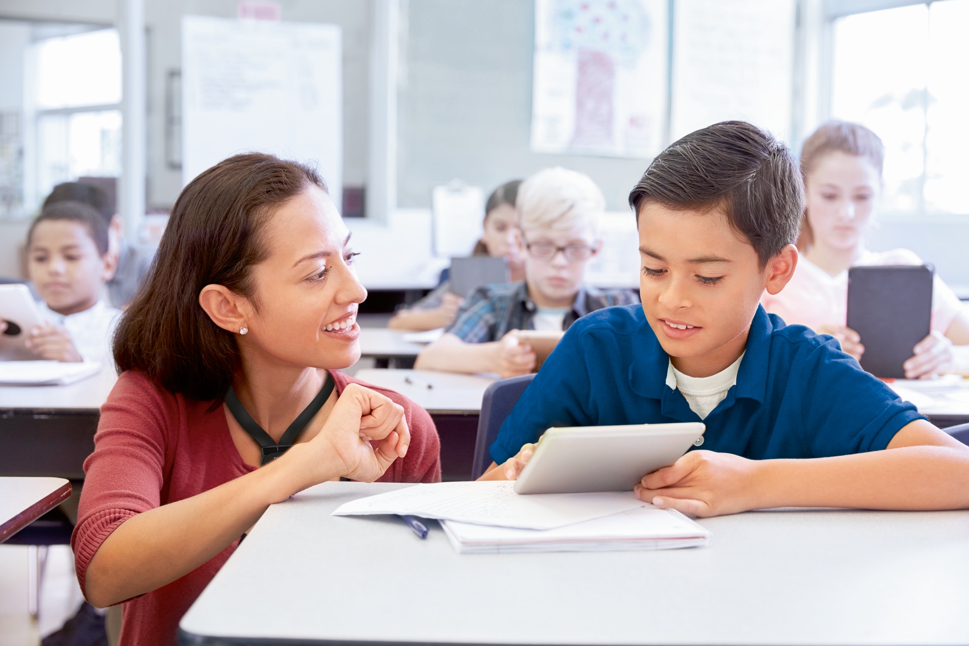 Female teacher helping one of her pupils in a classroom.