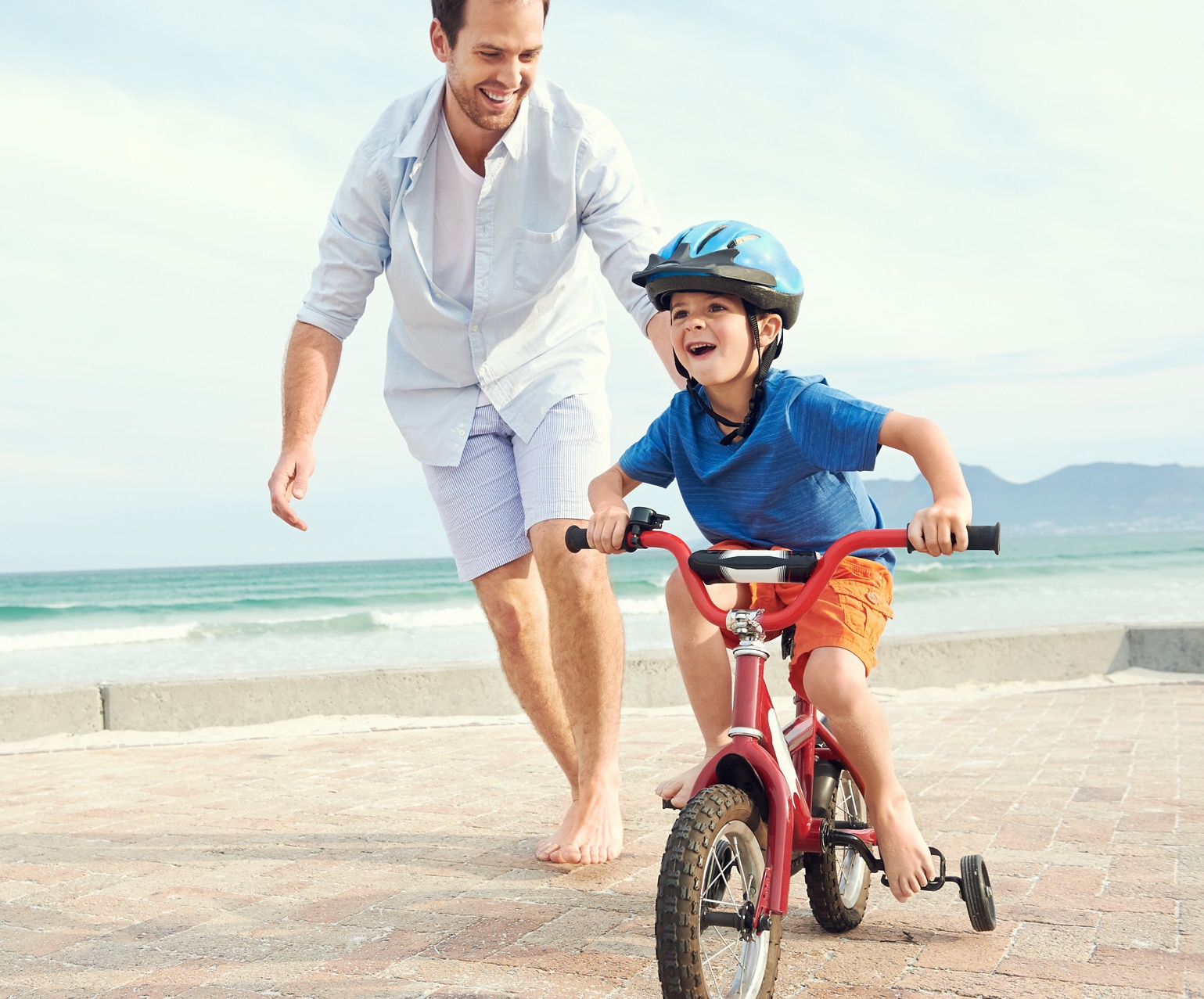 Father and son learning to ride a bicycle at the beach having fun together; Shutterstock ID 170208299; purchase_order: -; job: -; client: -; other: -