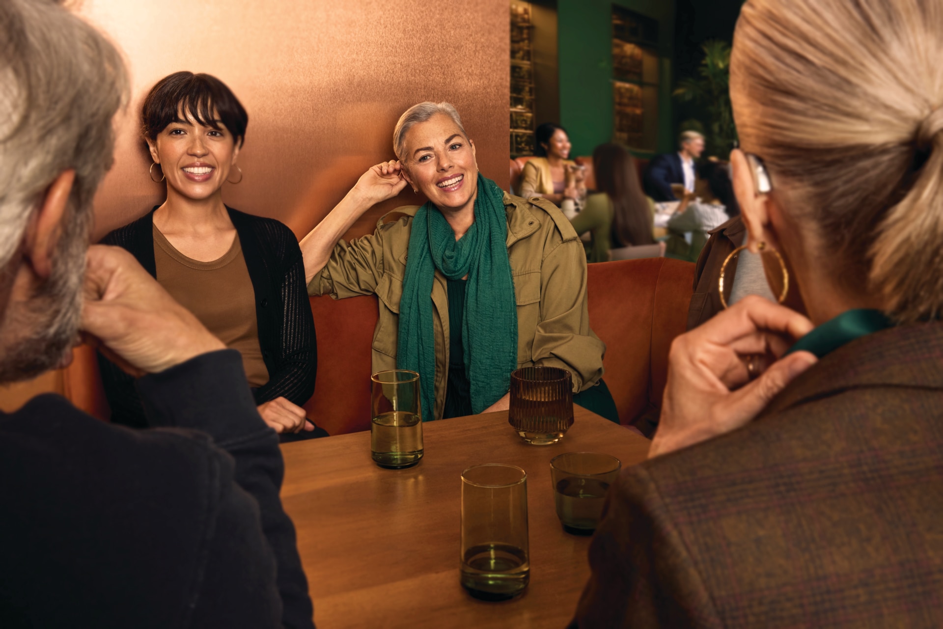  Image of women in a group conversation around a coffee table, illustrating how AutoSense OS AI 8.0 in Phonak Audéo EON helps maintain speech-focused settings when background noise levels briefly fluctuate.