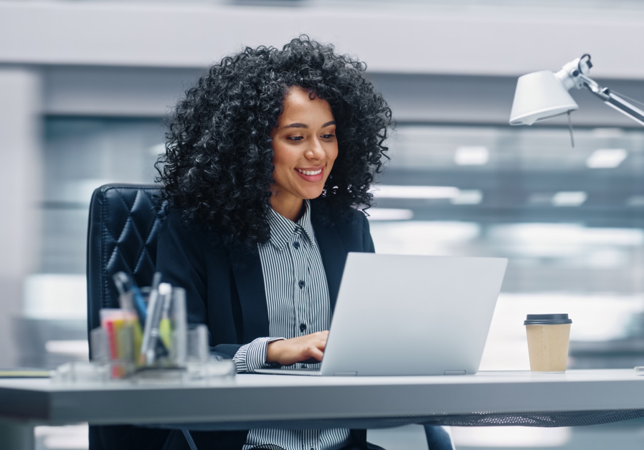 Black Businesswoman Sitting at Her Desk Working on a Laptop Computer