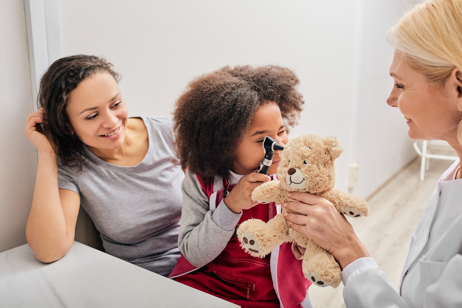 ENT doctor checking African female kid's ear using an otoscope. Hearing exam for children