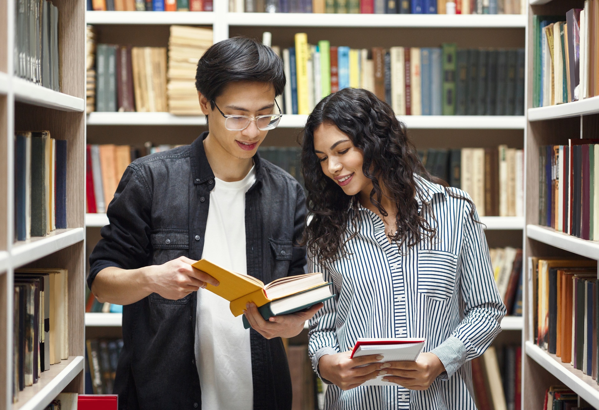 Programme d'échange d'étudiants. Deux étudiants multiraciaux debout dans une bibliothèque universitaire.