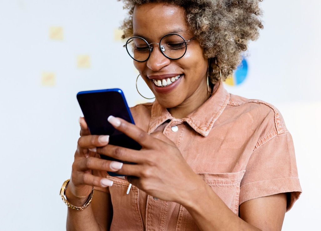 Smiling female entrepreneur using smart phone at home office