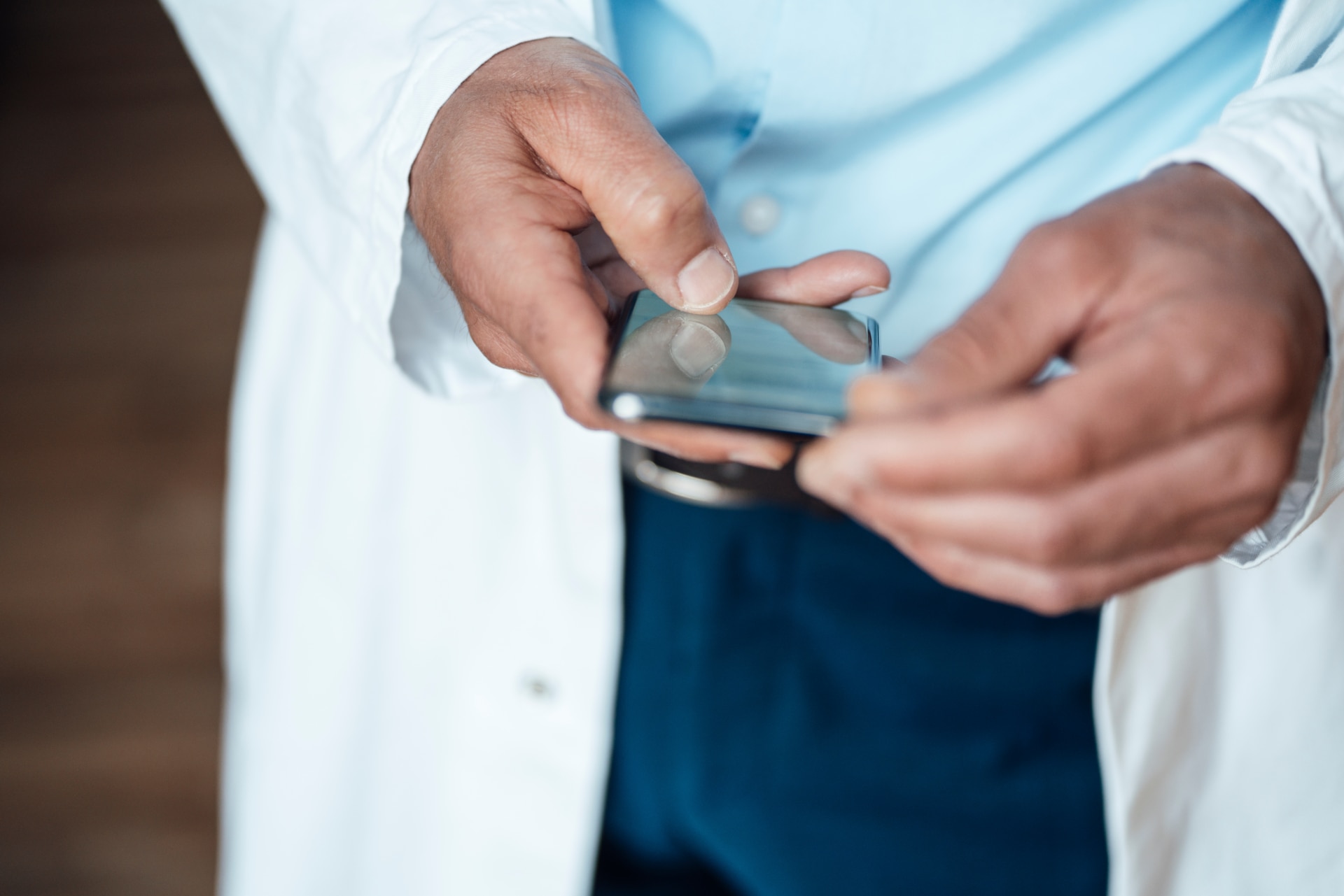 Primer plano de las manos de un médico sosteniendo un smartphone.