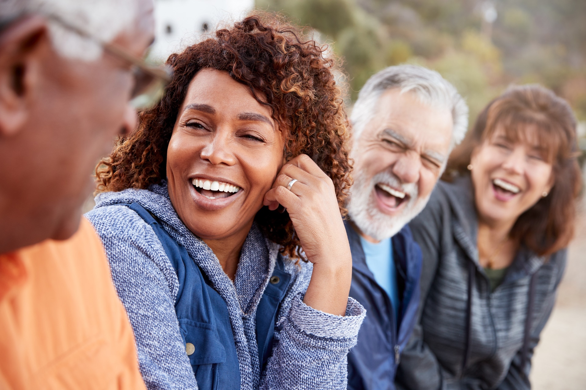 Grupo de amigos de edad avanzada de excursión en el campo hablando y riendo juntos