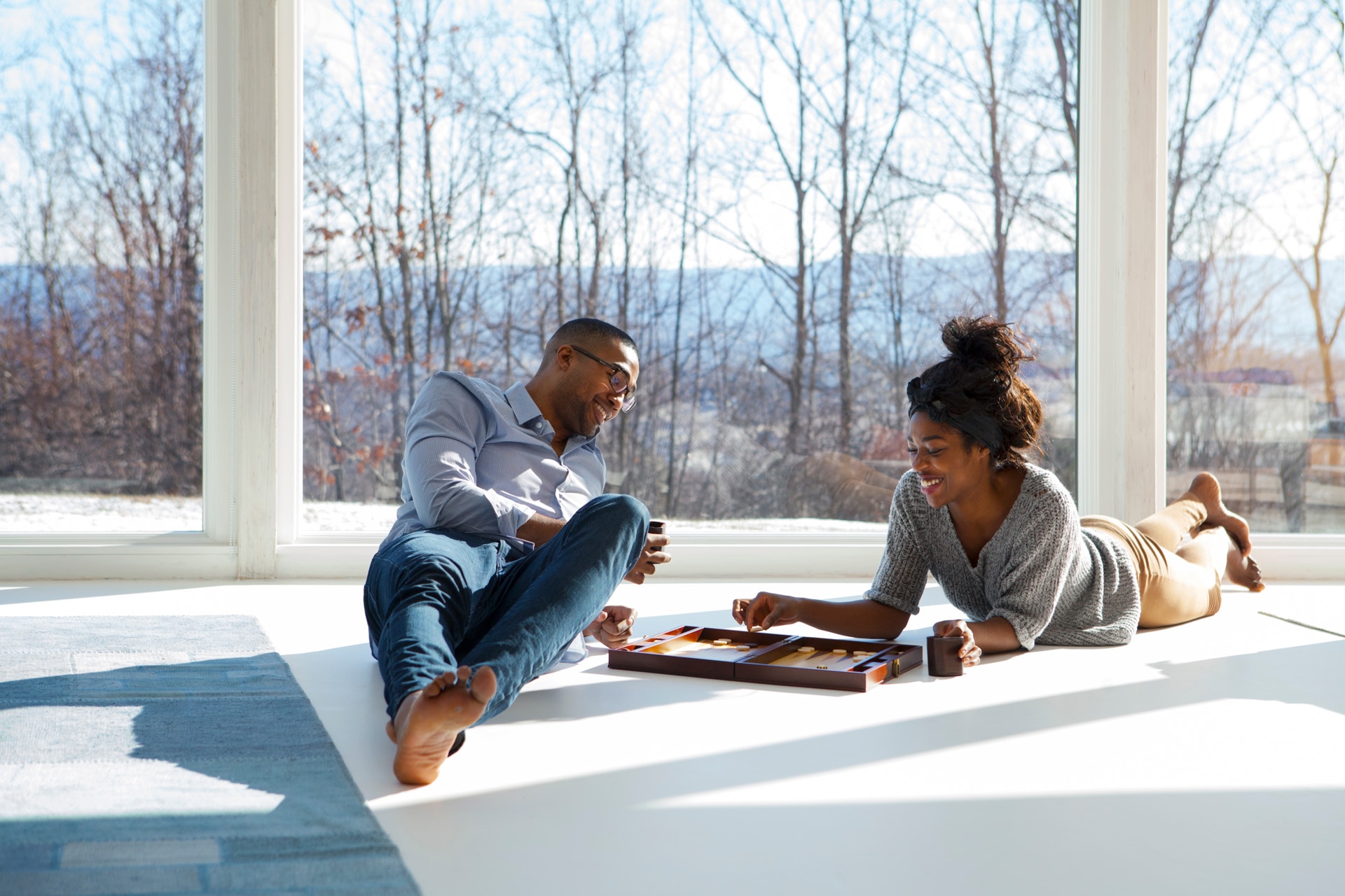 A couple plays backgammon on their living room floor