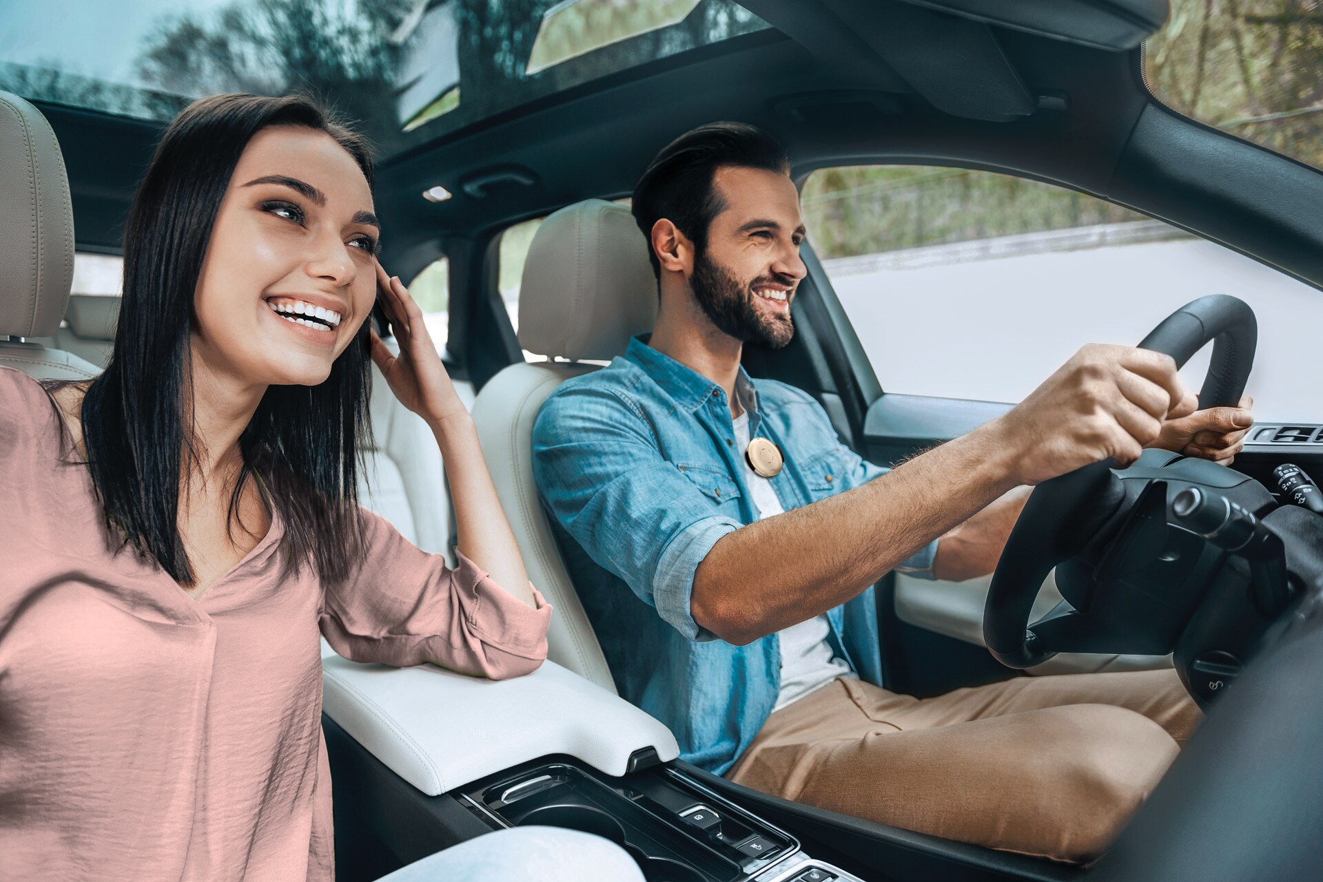 Young couple in a car - male is driving and has Roger Select clipped to his shirt.