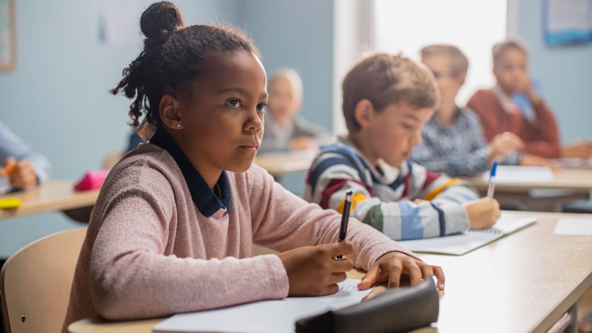 In Elementary School Classroom Brilliant Black Girl Writes in Exercise Notebook, Taking Test and Writing Exam. Junior Classroom with Diverse Group of Children Working Diligently and Learning New Stuff; Shutterstock ID 1767333926; purchase_order: -; job: -; client: -; other: