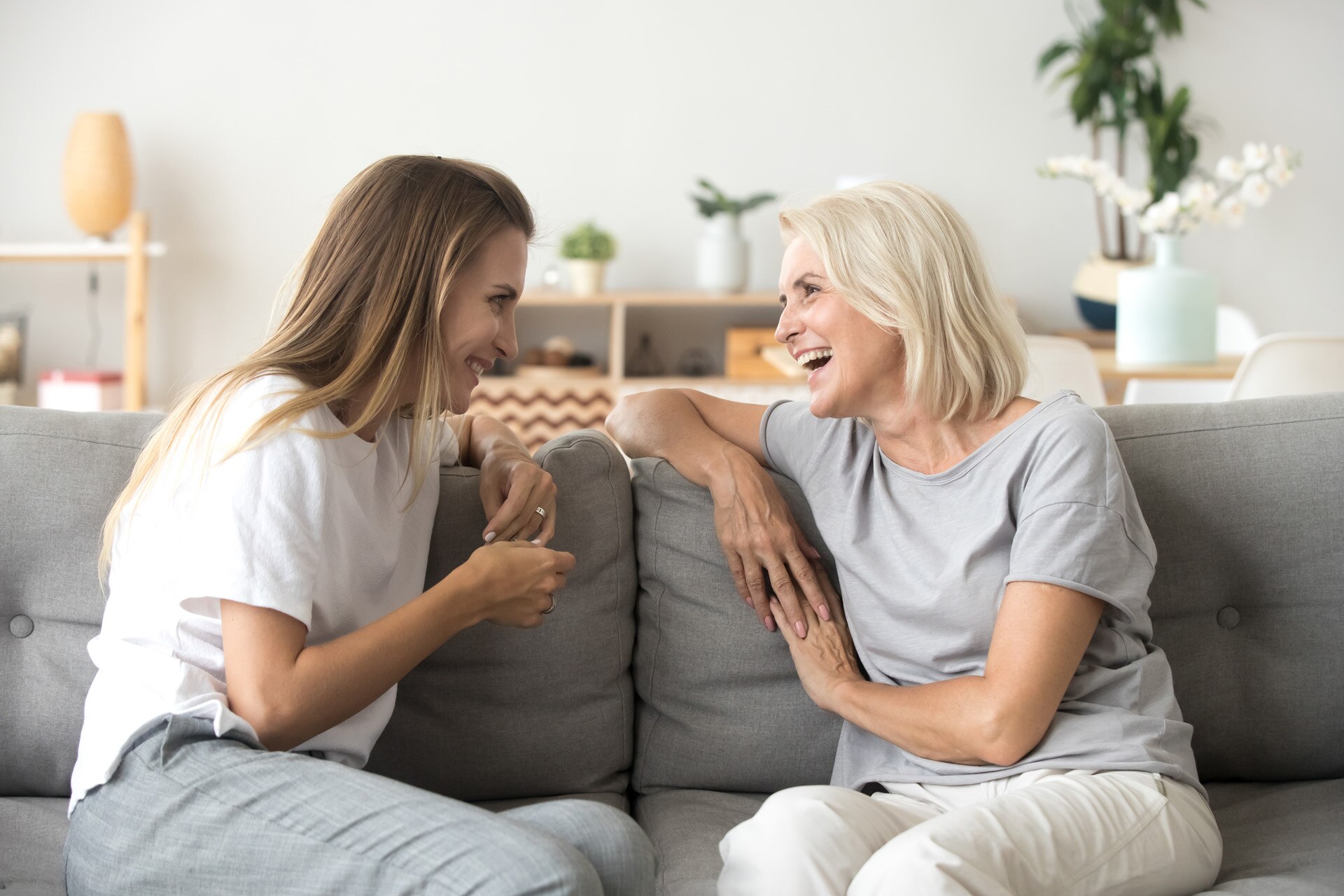 Cheerful old mother and young adult woman talking laughing together, smiling elderly older mum having fun chatting with grown daughter, two age generations pleasant conversation at home concept; Shutterstock ID 1231591396; purchase_order: -; job: -; client: -; other: -