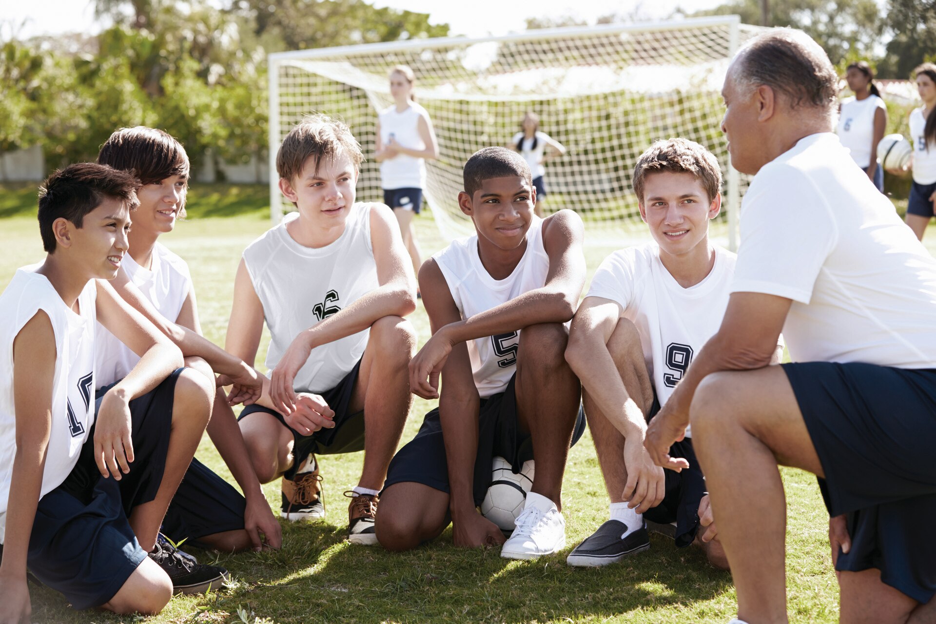 Young football players being coached by their trainer.