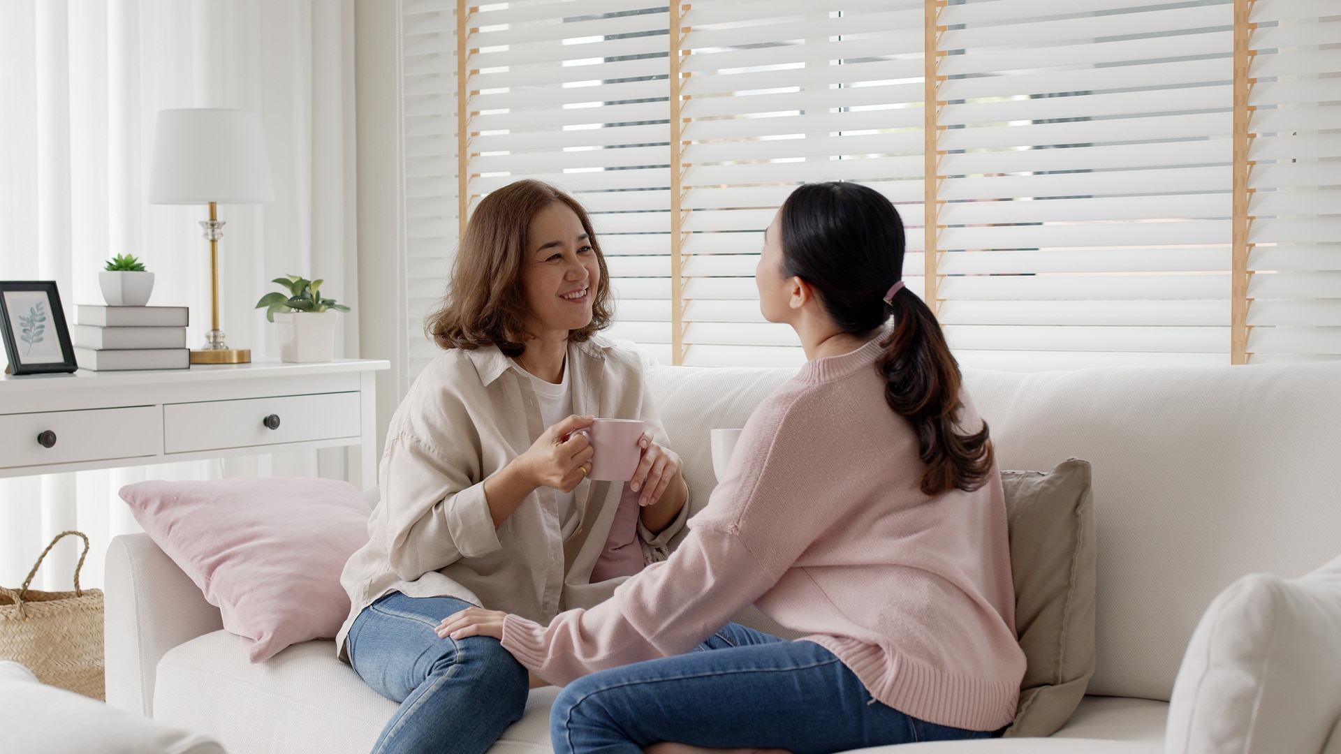 Une jeune personne âgée est assise pour avoir une conversation familiale tendre et authentique avec ses enfants adultes dans le salon, et se sent positive et détendue alors qu’elle écoute sa fille.