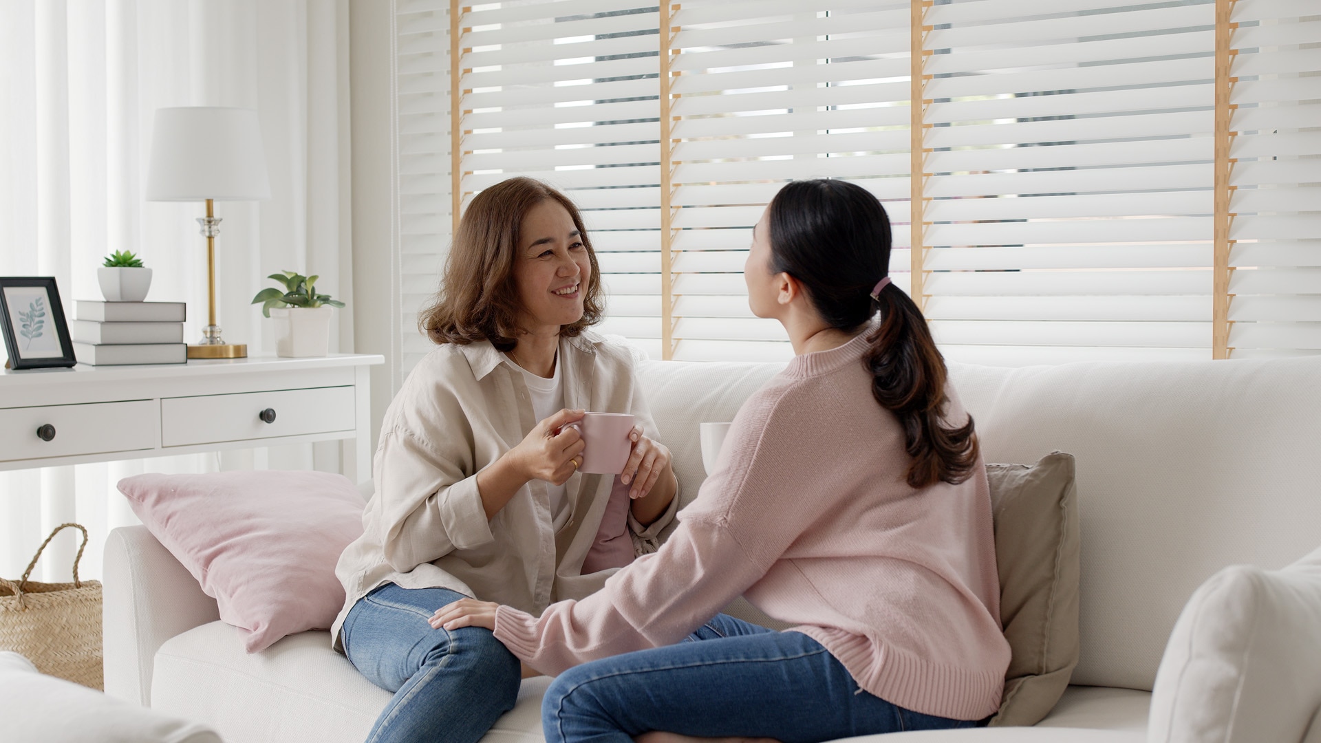 Une jeune personne âgée est assise pour avoir une conversation familiale tendre et authentique avec ses enfants adultes dans le salon, et se sent positive et détendue alors qu’elle écoute sa fille. 