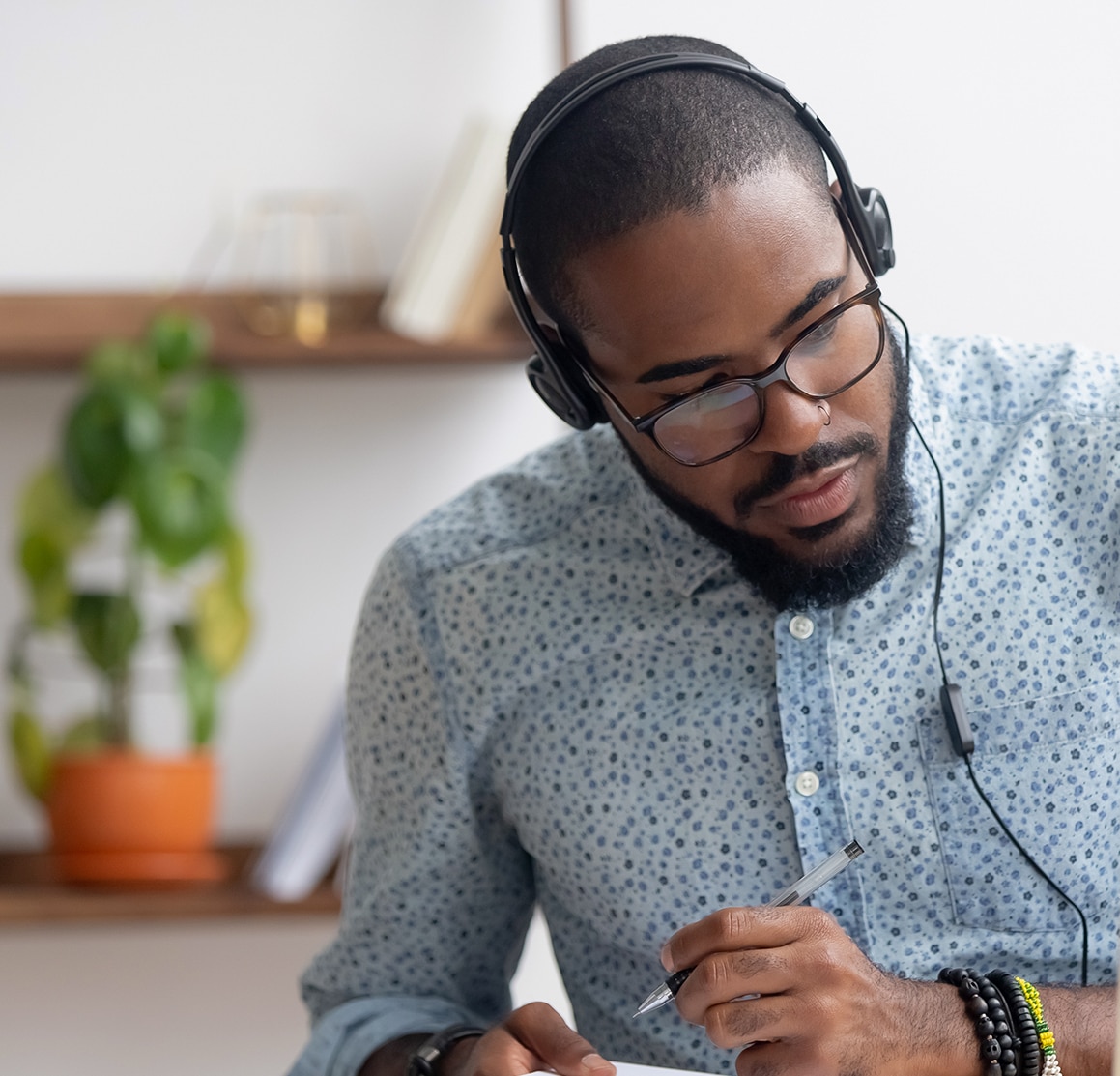 Focused african business man in headphones writing notes in notebook watching webinar video course, serious black male student looking at laptop listening lecture study online on computer e learning; Shutterstock ID 1368244235; purchase_order: -; job: -; client: -; other: -