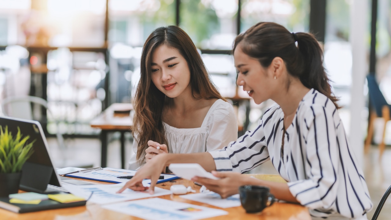 Two young Asian businesswoman discuss investment project working and planning strategy. Business people talking together with laptop computer at office.; Shutterstock ID 2086945537; purchase_order: -; job: -; client: -; other: -