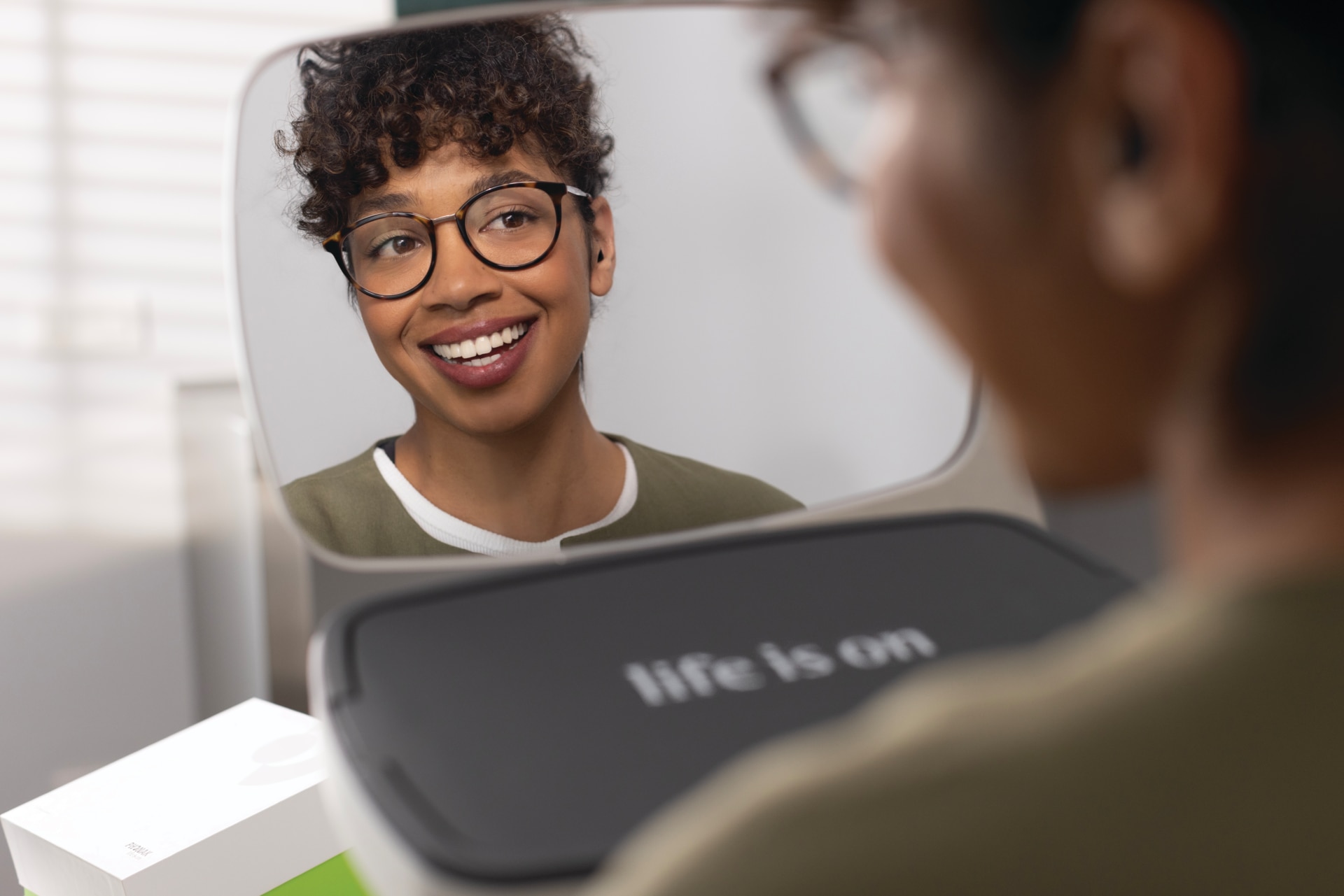 Une femme heureuse portant une prothèse Phonak Virto et regardant dans le miroir