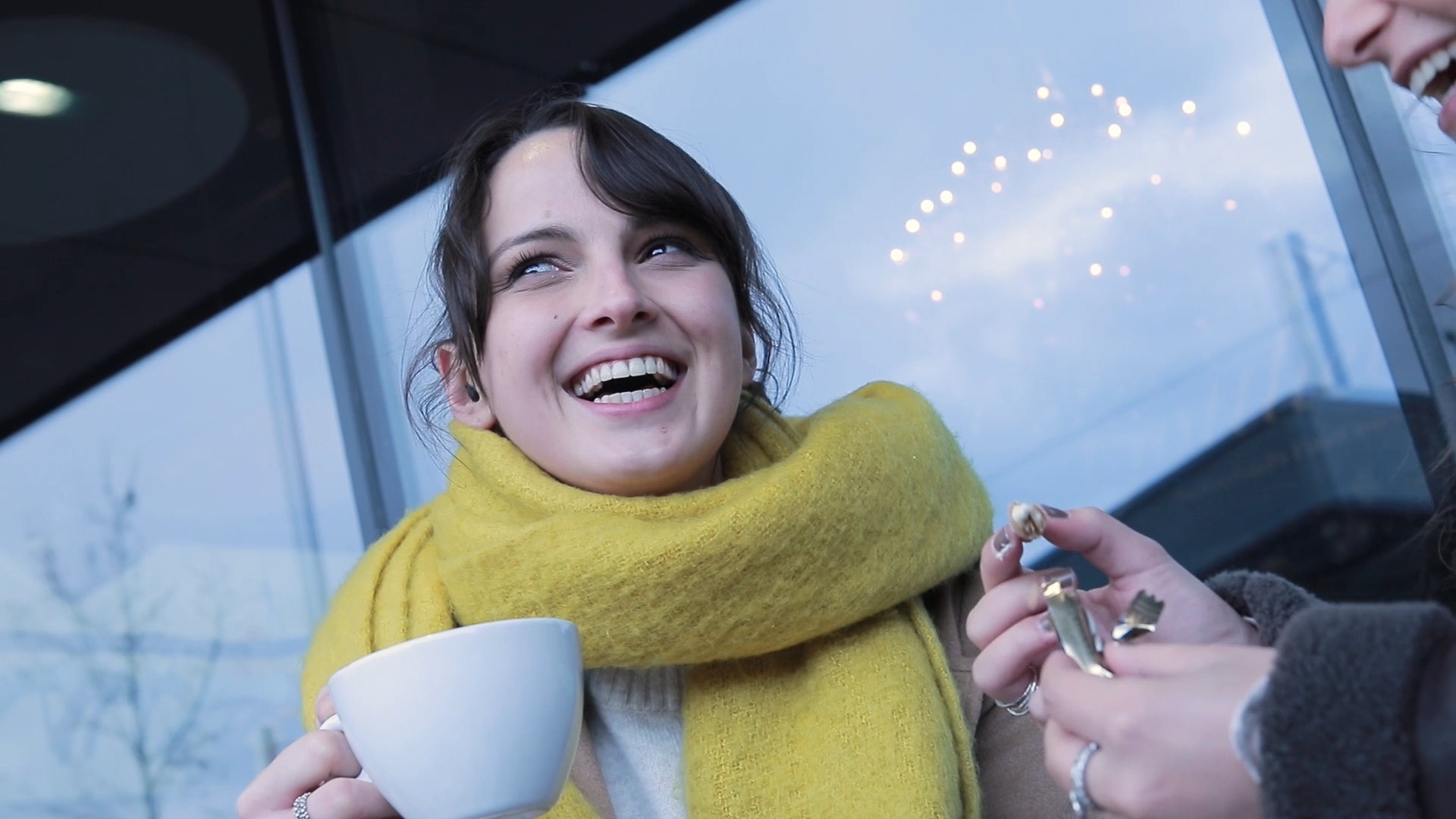 Utilisatrice heureuse de Phonak Virto pendant une conversation avec son amie sur la terrasse d’un café.