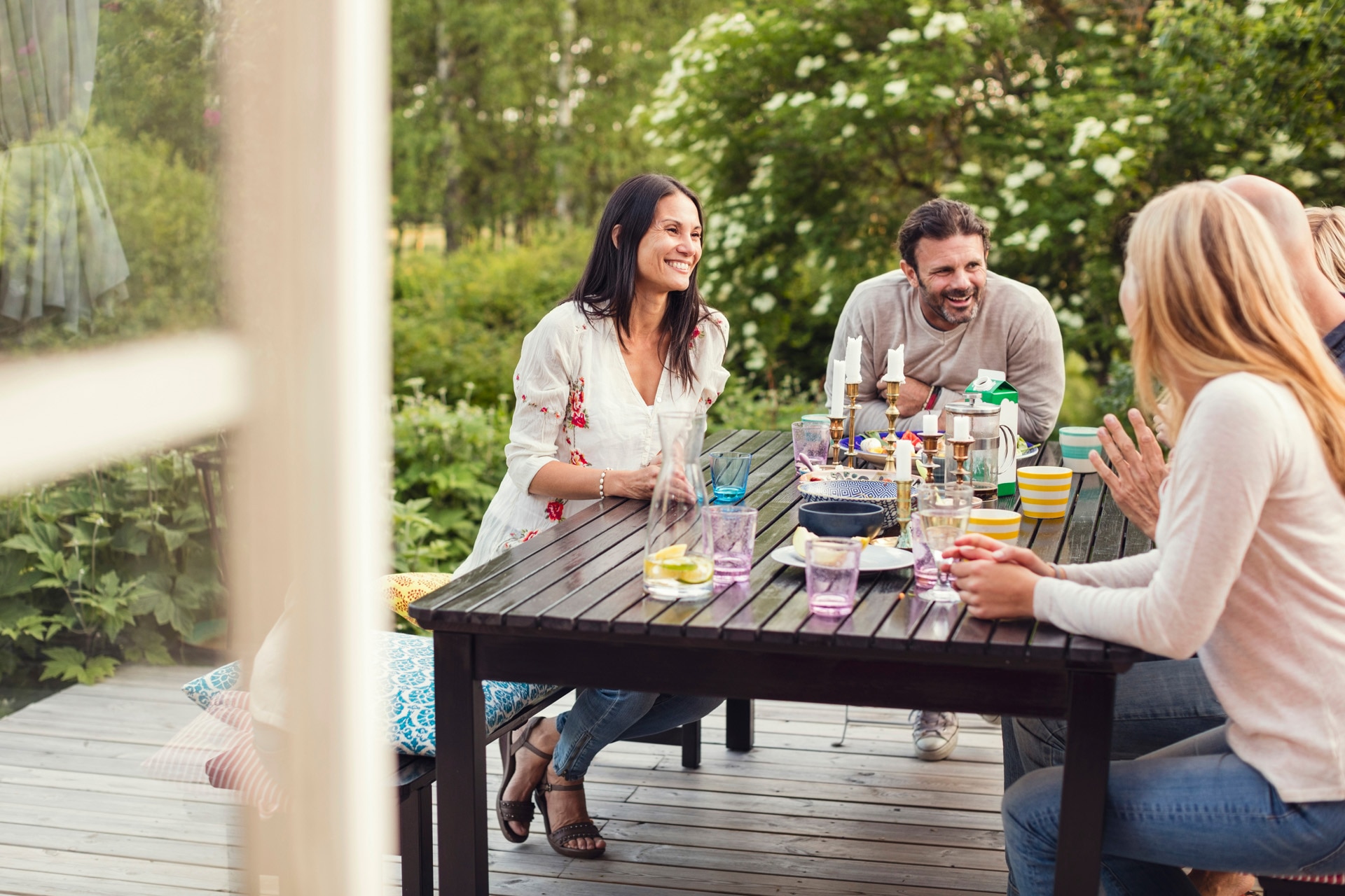 Familie und Freunde sitzen fröhlich beim Abendessen im Garten hinter dem Haus