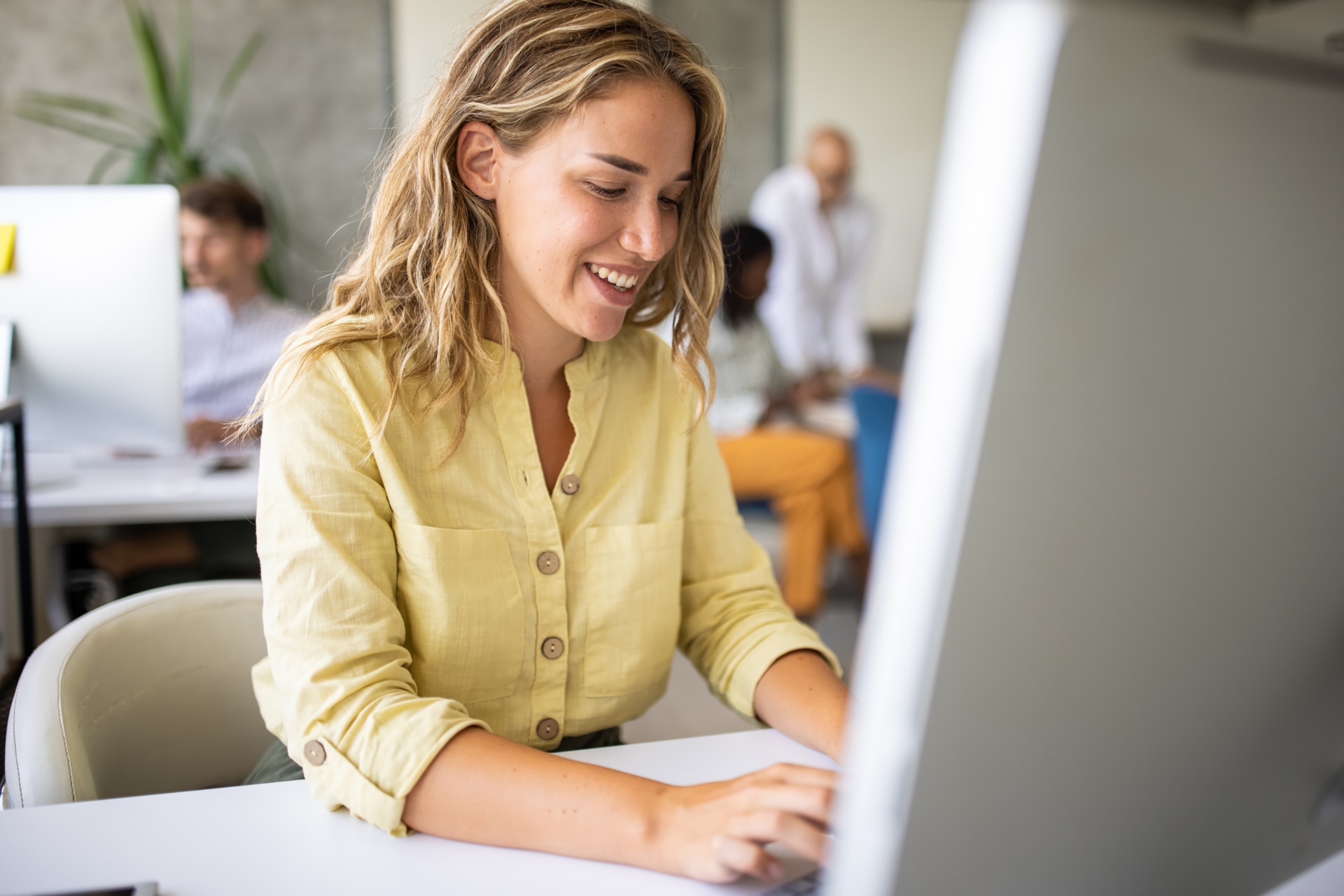 1334658380 Geschäftsfrau arbeitet am Computer in einem offenen Arbeitsplatz.