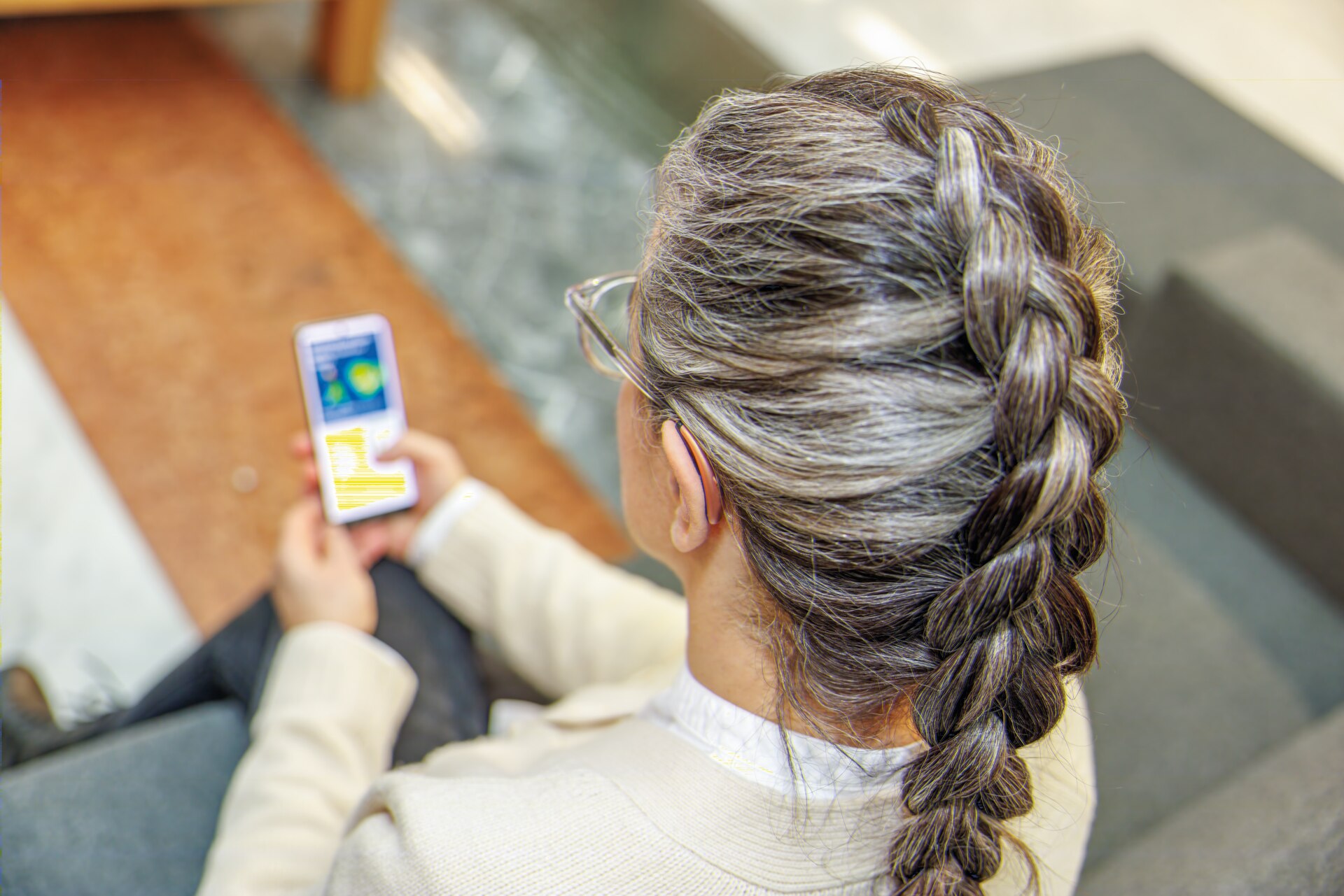 Frau mit kleinem Hörsystem und Smartphone