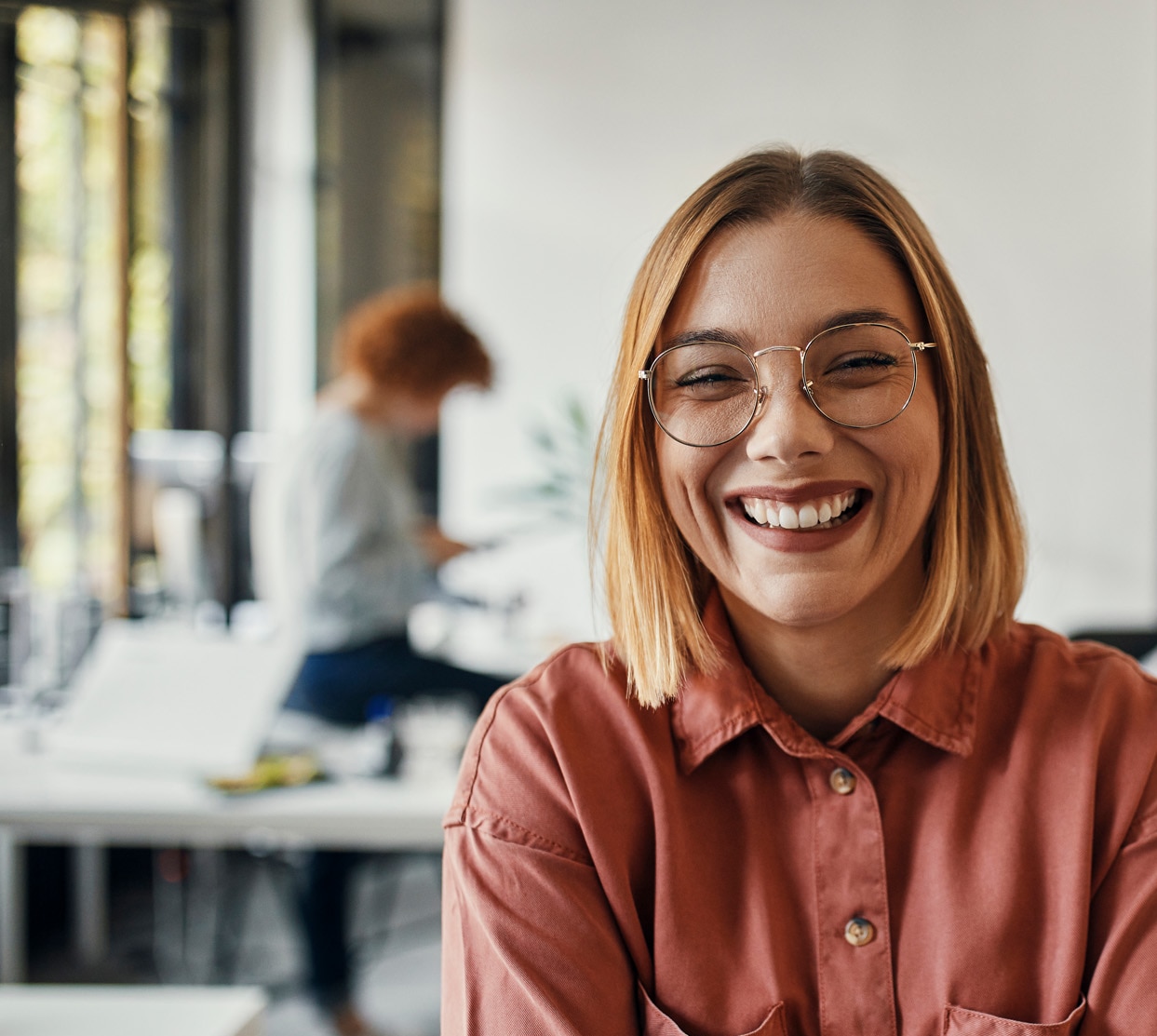 Portrait of a happy businesswoman in office with colleagues in background.