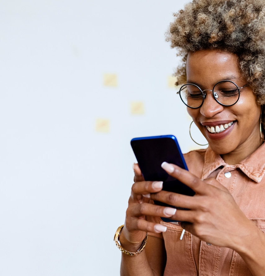 Smiling female entrepreneur using her smartphone at home office.