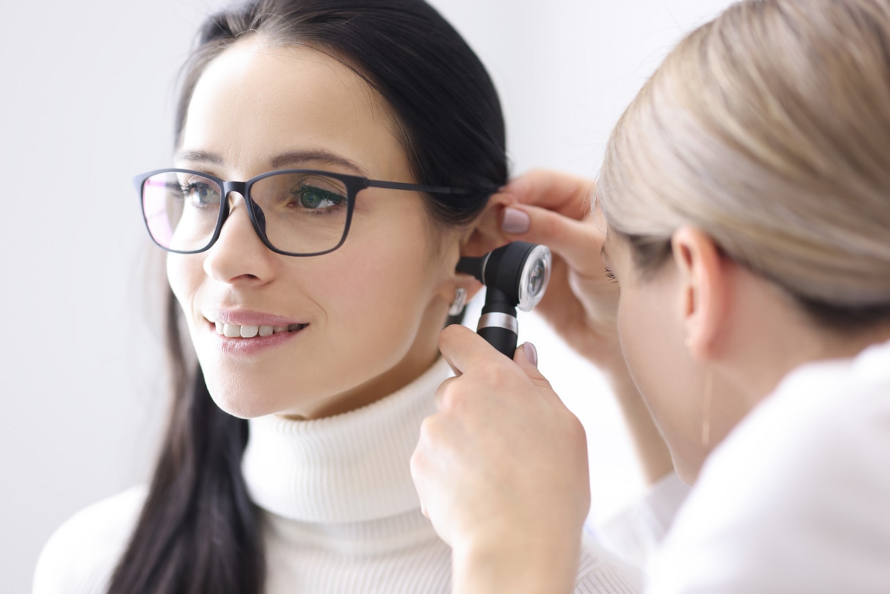 Doctor conducts examinations of ear area for woman