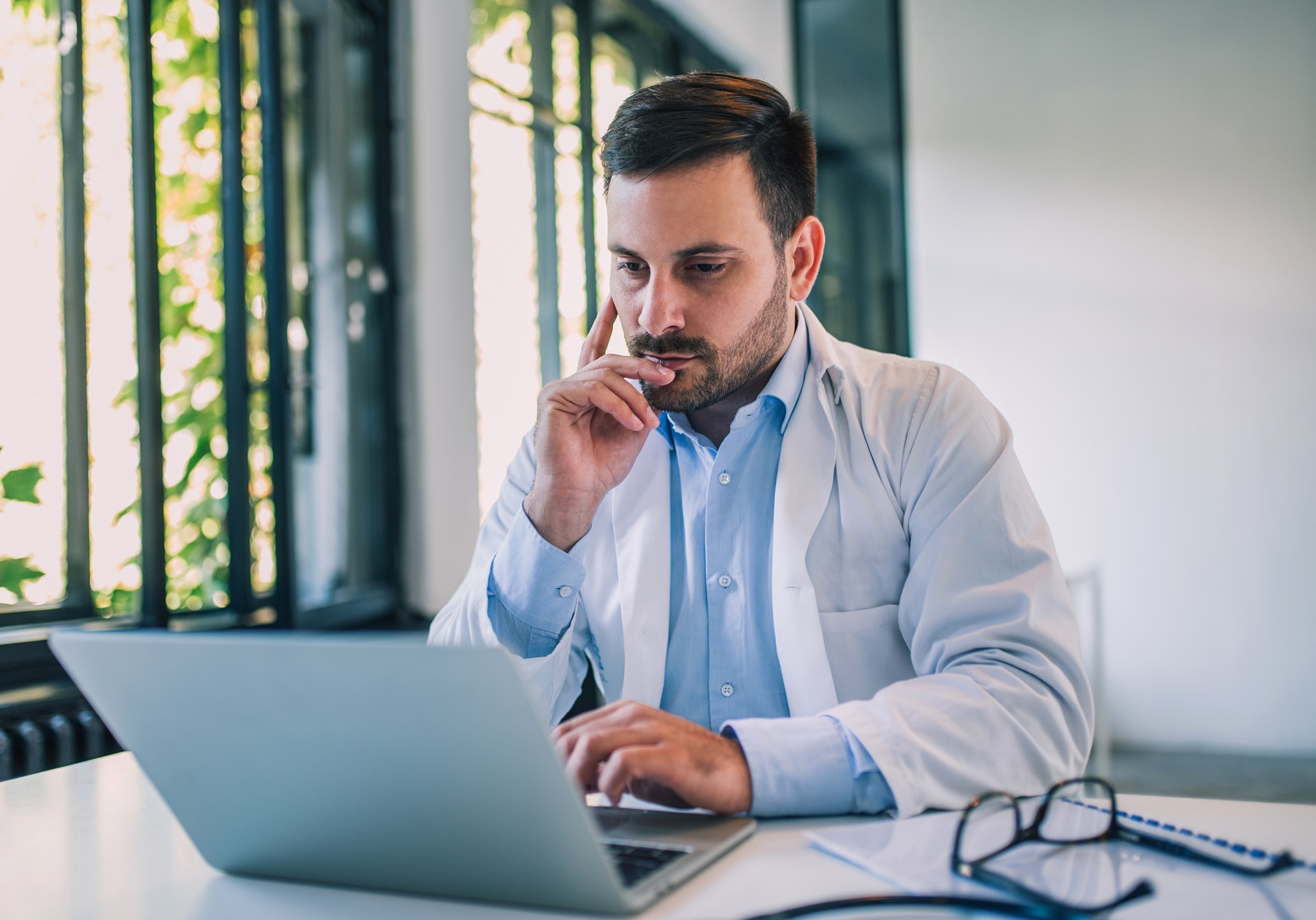 A serious doctor using a laptop in his office