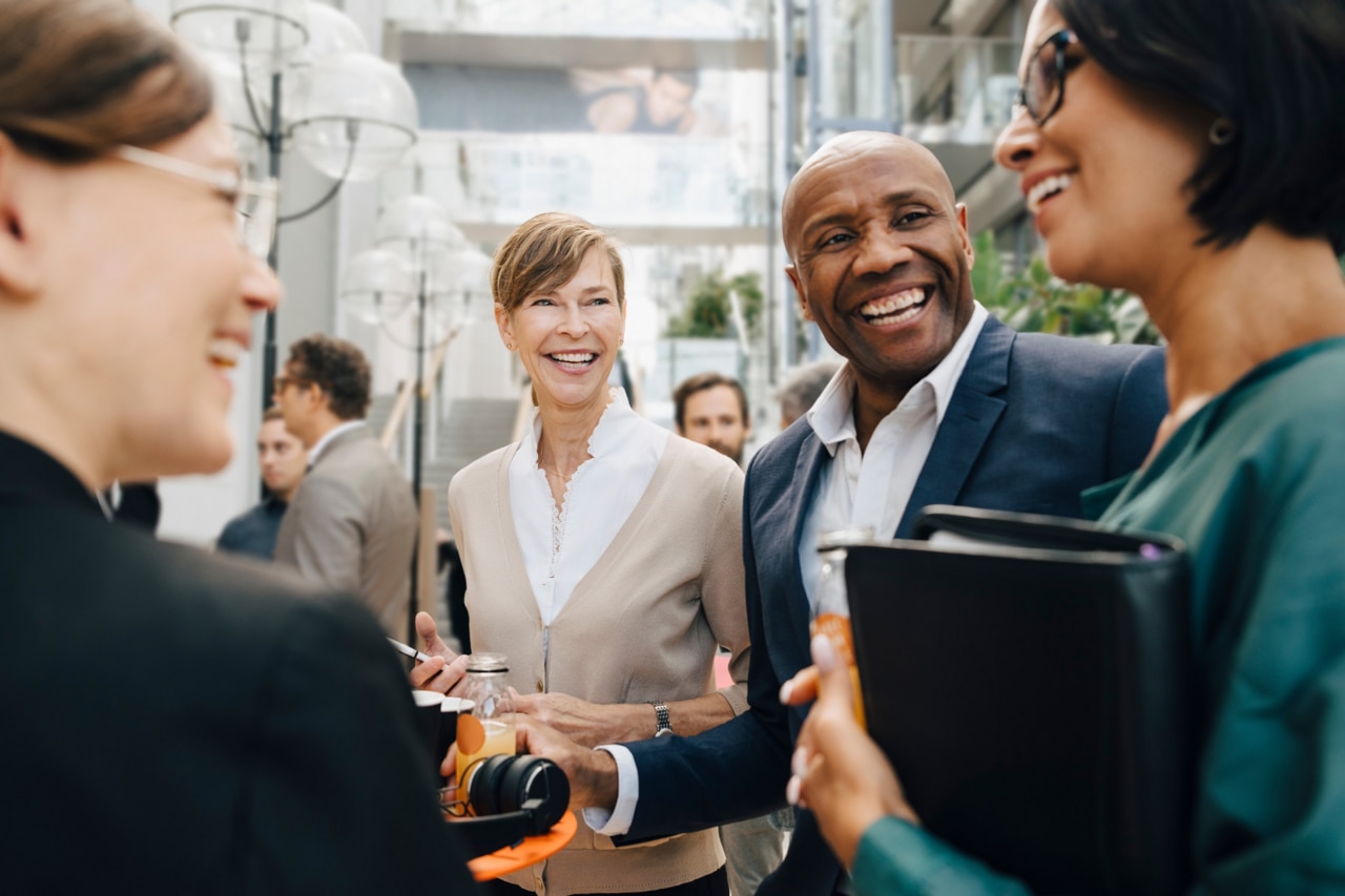 Happy male and female business people talking while standing in office