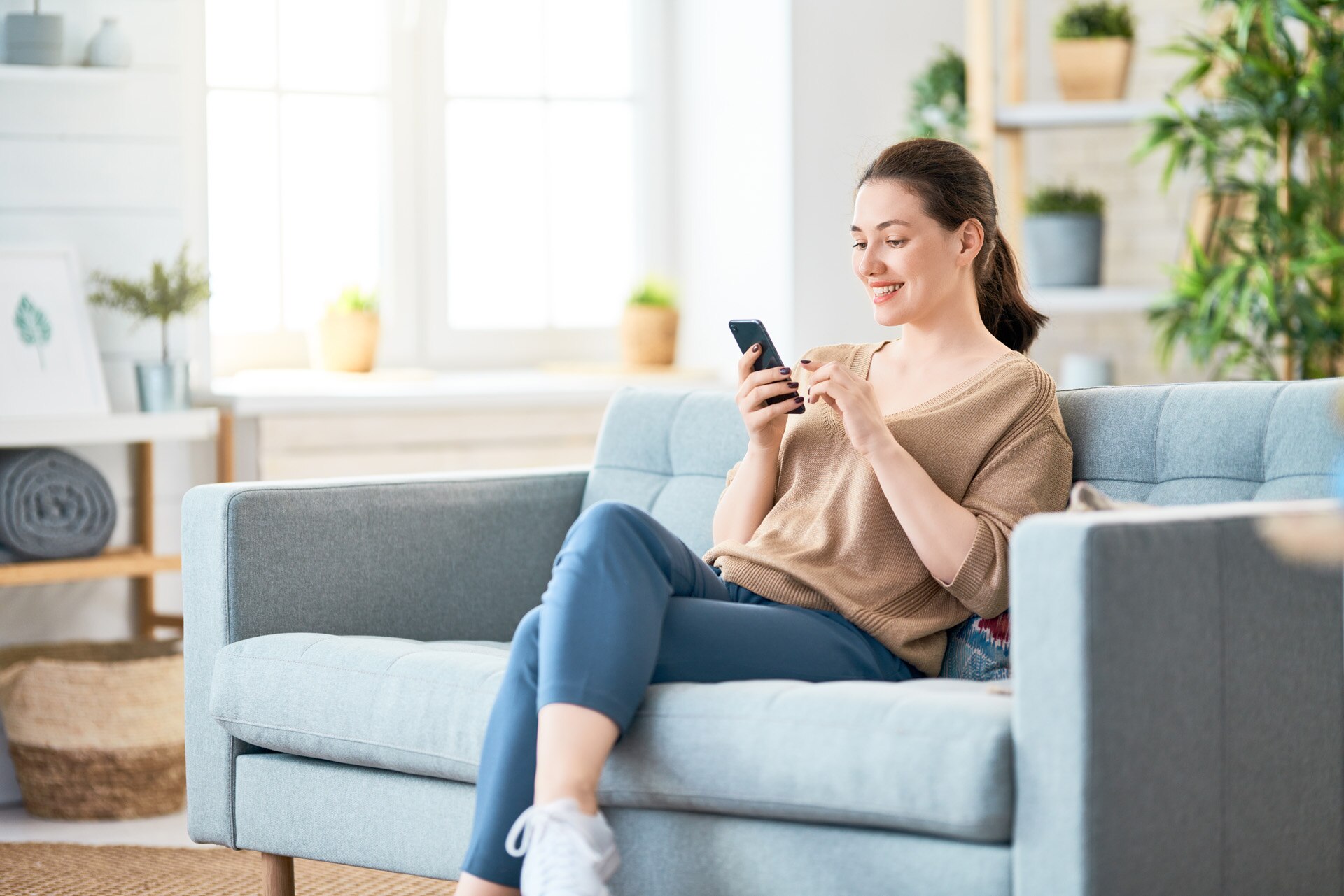 Happy casual beautiful woman is talking on a phone sitting on a sofa at home.; Shutterstock ID 1422270389; purchase_order: -; job: -; client: -; other: -