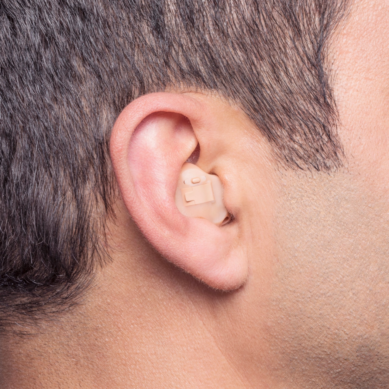 Close-up of middle aged male's ear with in-the-ear hearing aid.