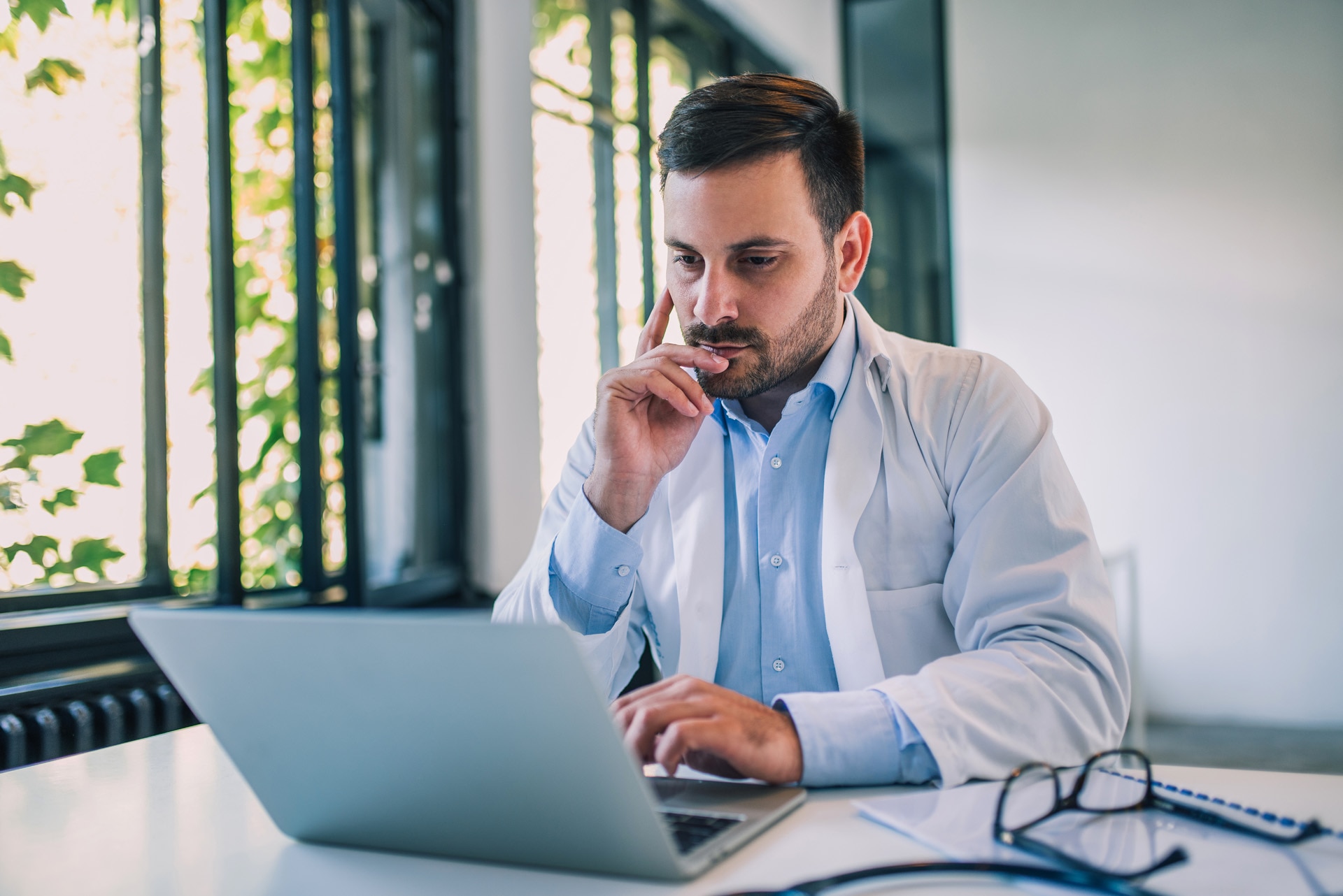 A serious doctor using a laptop in his office