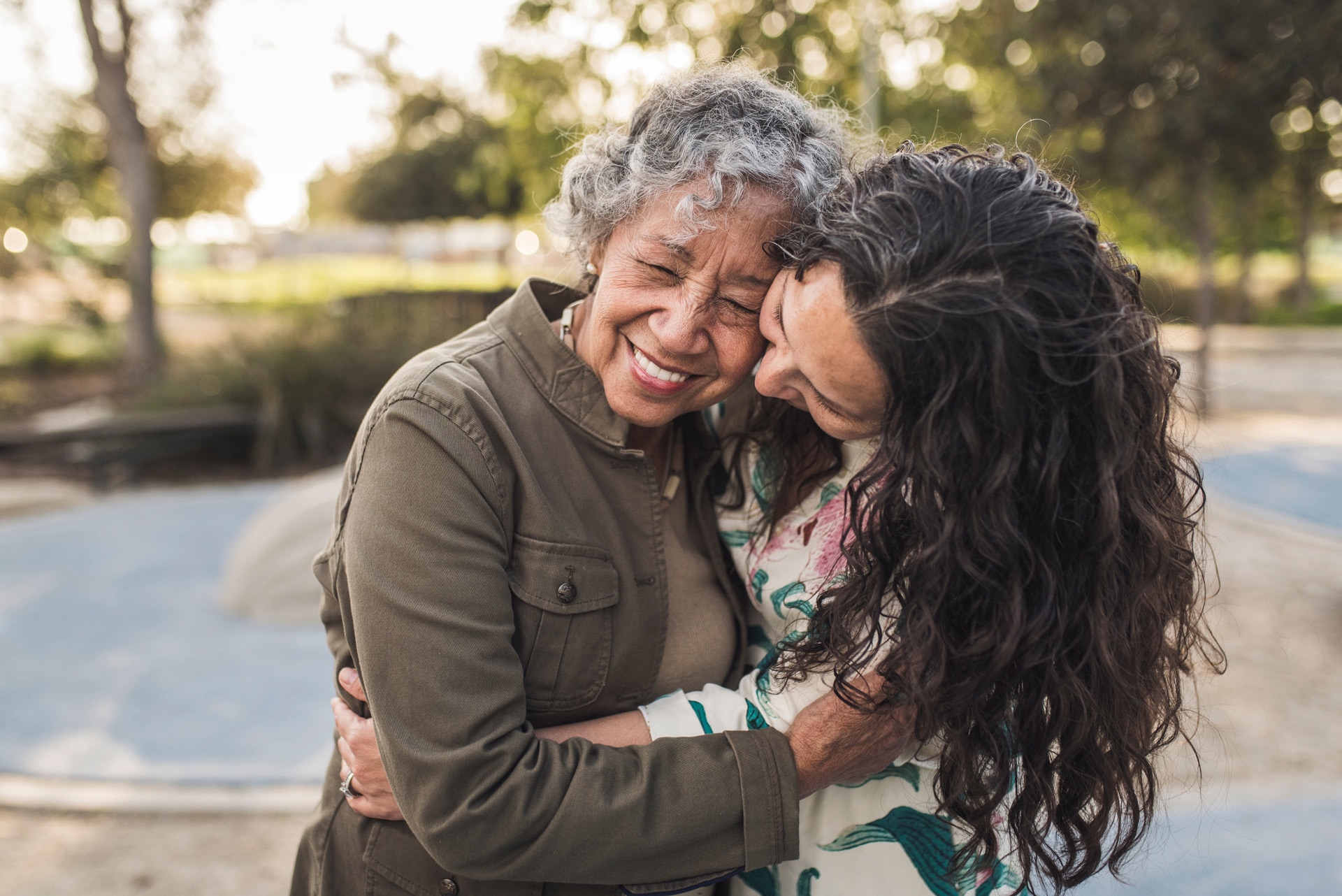 Happy daughter embracing senior mother in a park.