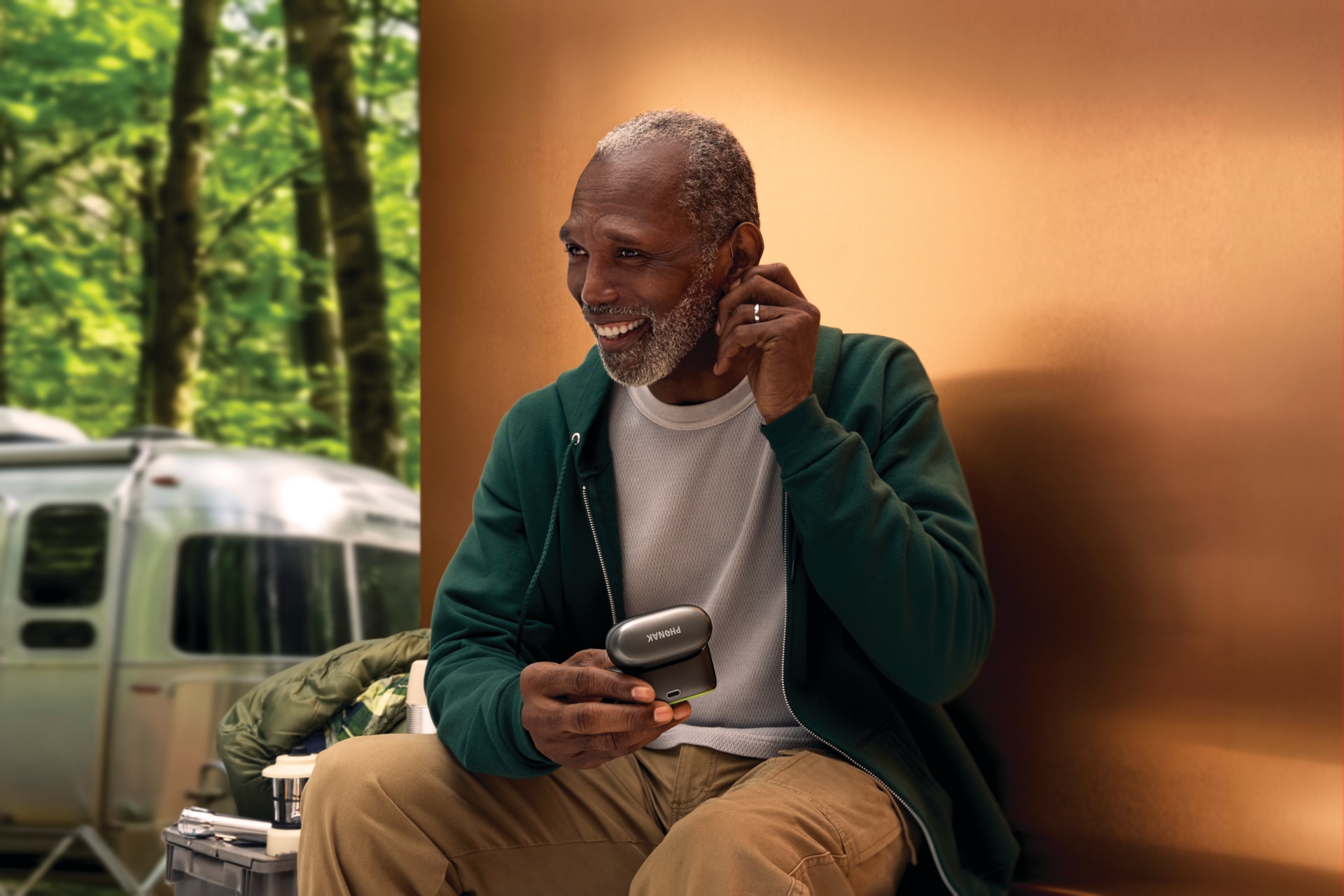 Person, der bruger Phonak Audéo™ EON R høreapparater sammen med en smartphone udendørs.
