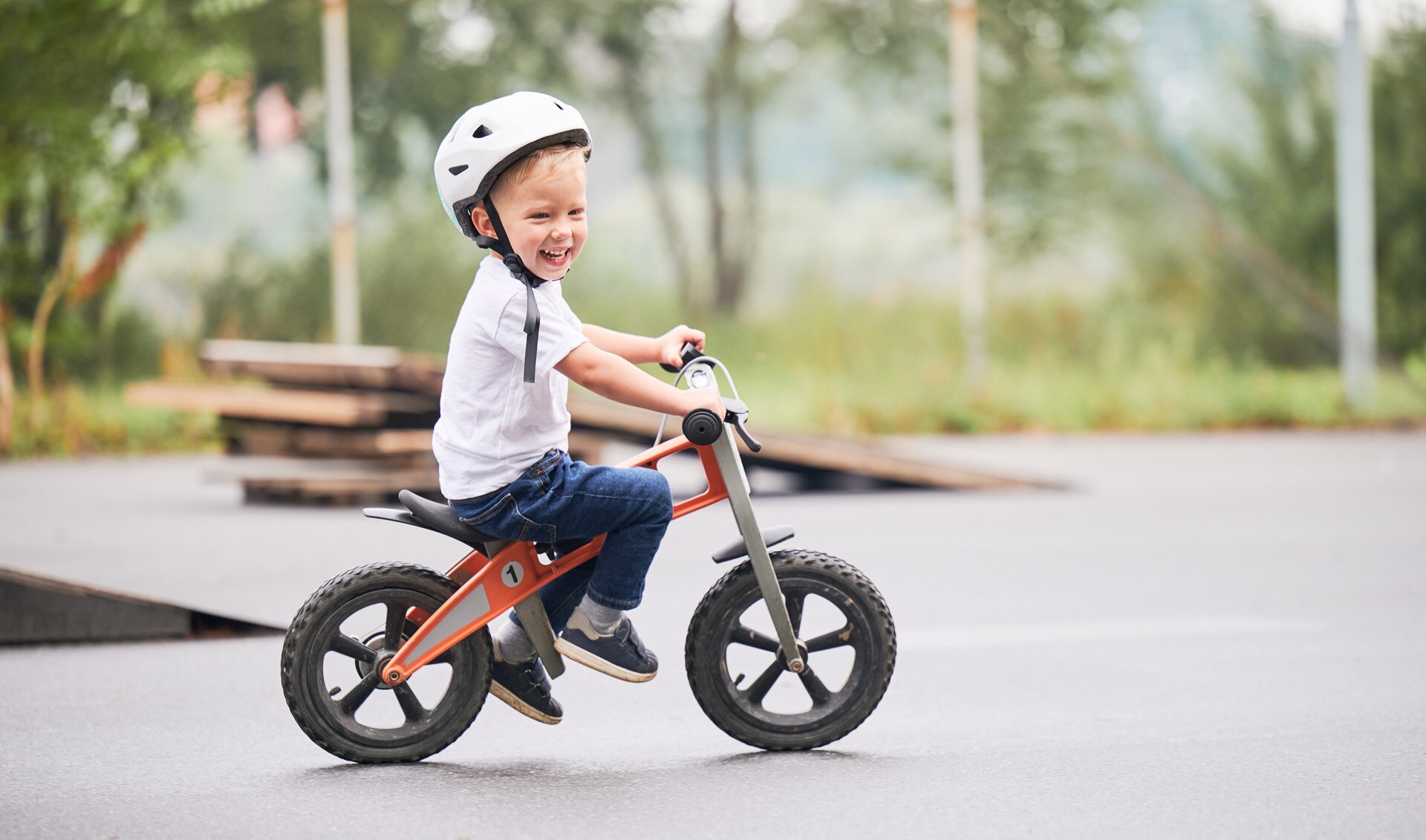 Happy child riding balance bike. Male toddler kid in helmet learning to ride on run bicycle at skate park.; Shutterstock ID 2167754077; purchase_order: -; job: -; client: -; other: -