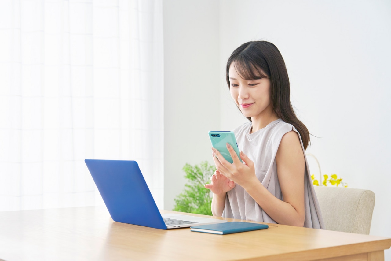 Otthonában okostelefont használó ázsiai nő