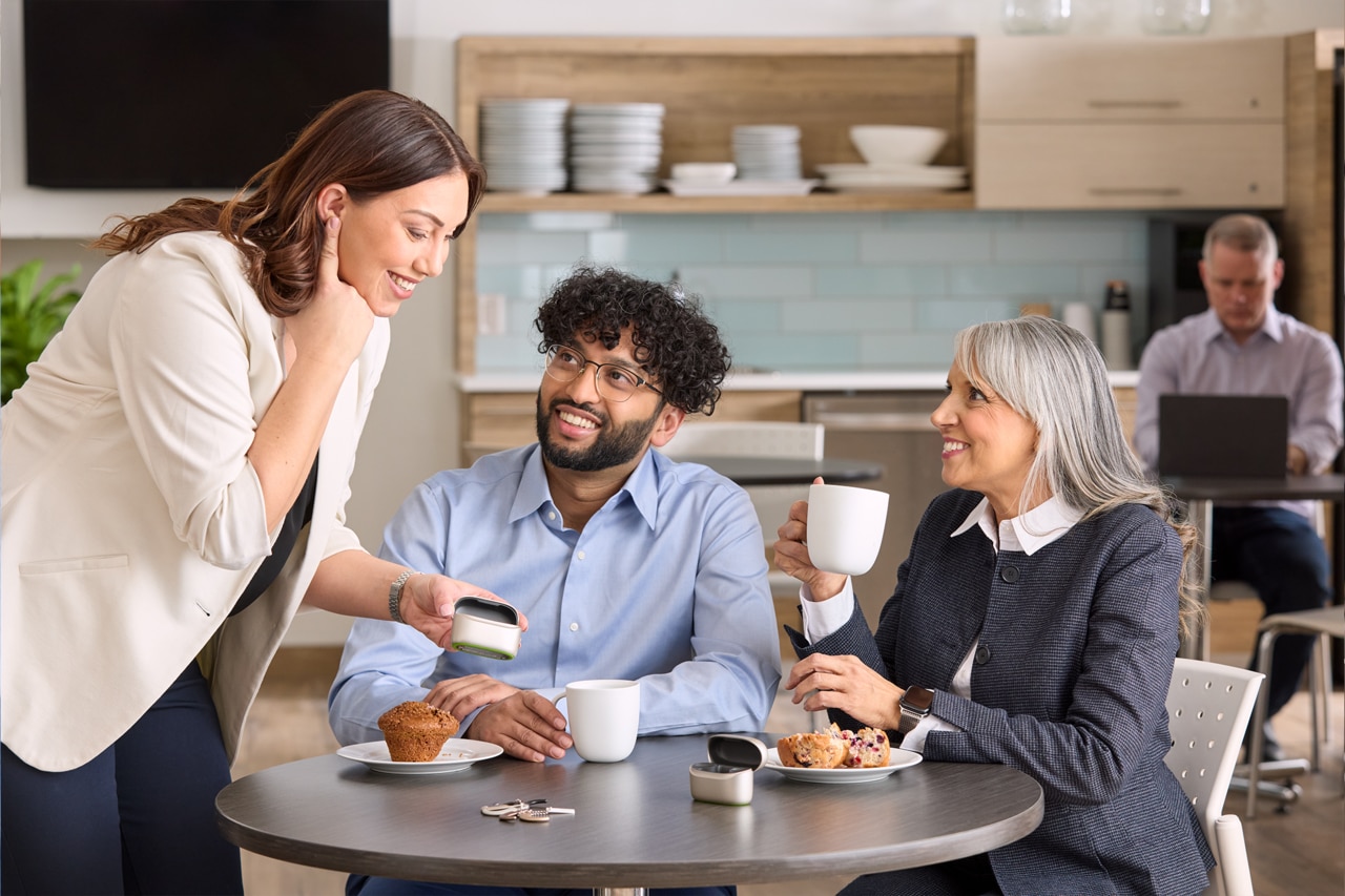 Casual breakroom chat reviewing hearing aid devices