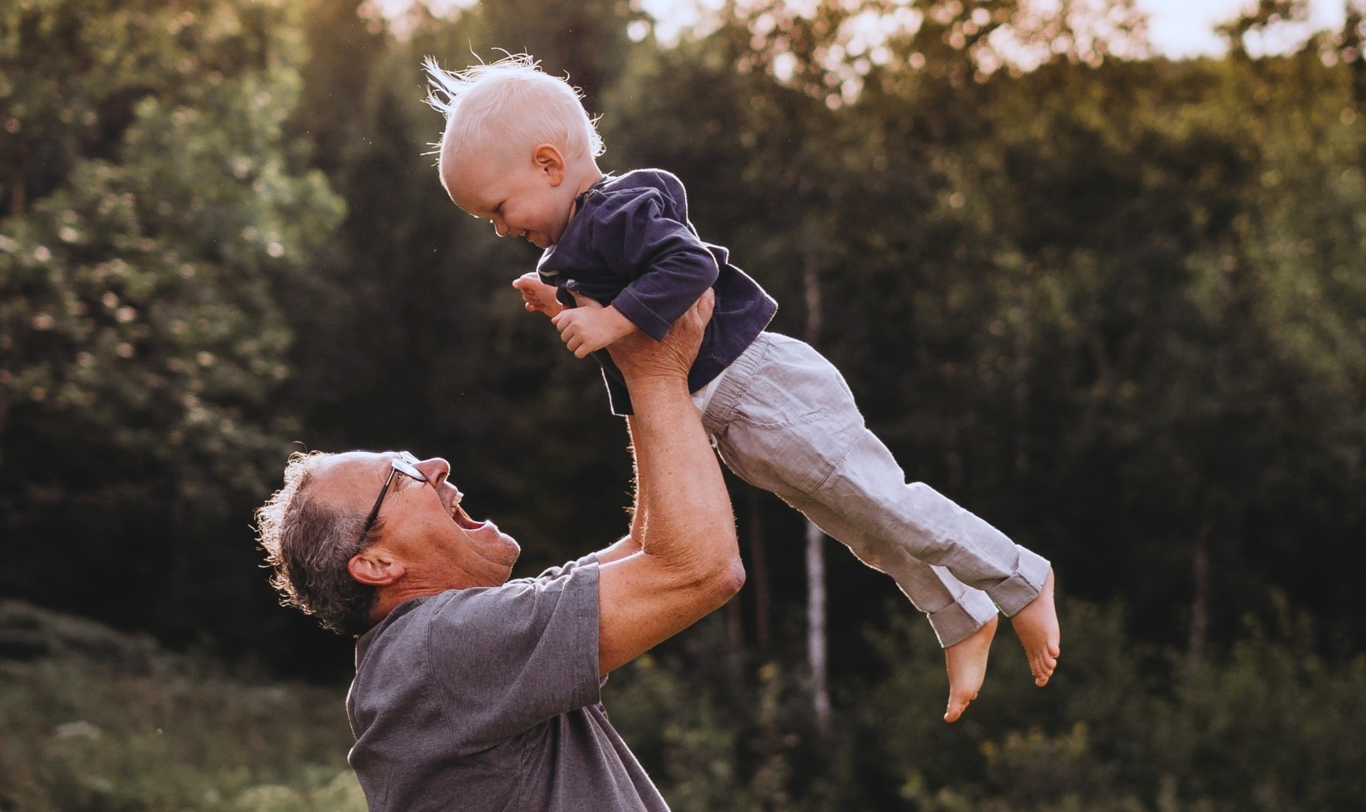 A grandfather playing with his little grandson in the garden