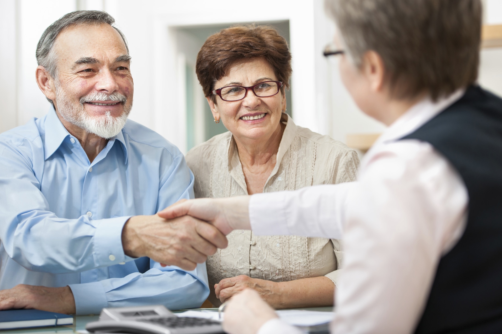 A couple during a visit at a hearing care professional, smiling, shaking hands