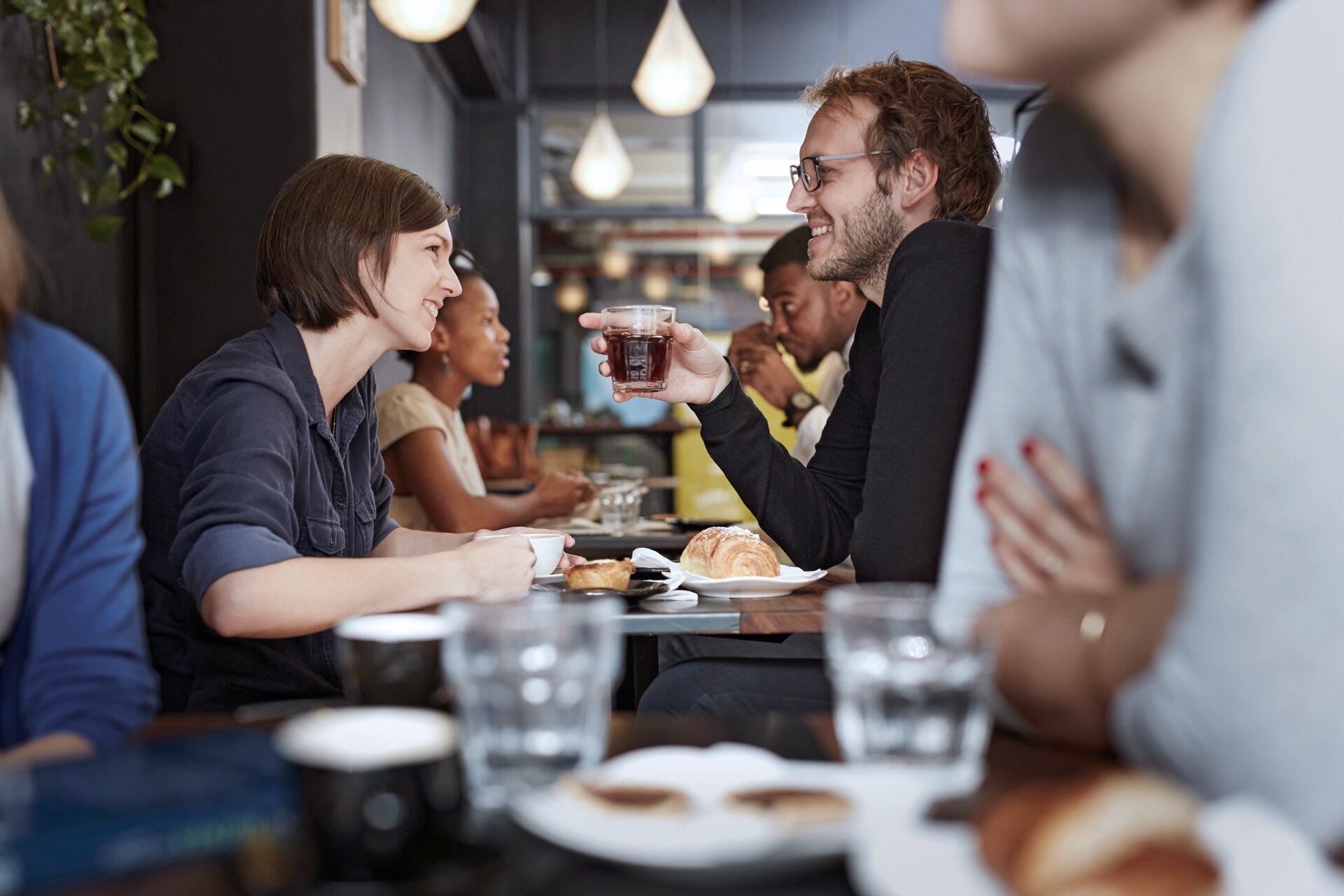 Man and a woman sitting across from one another in a noisy restaurant.