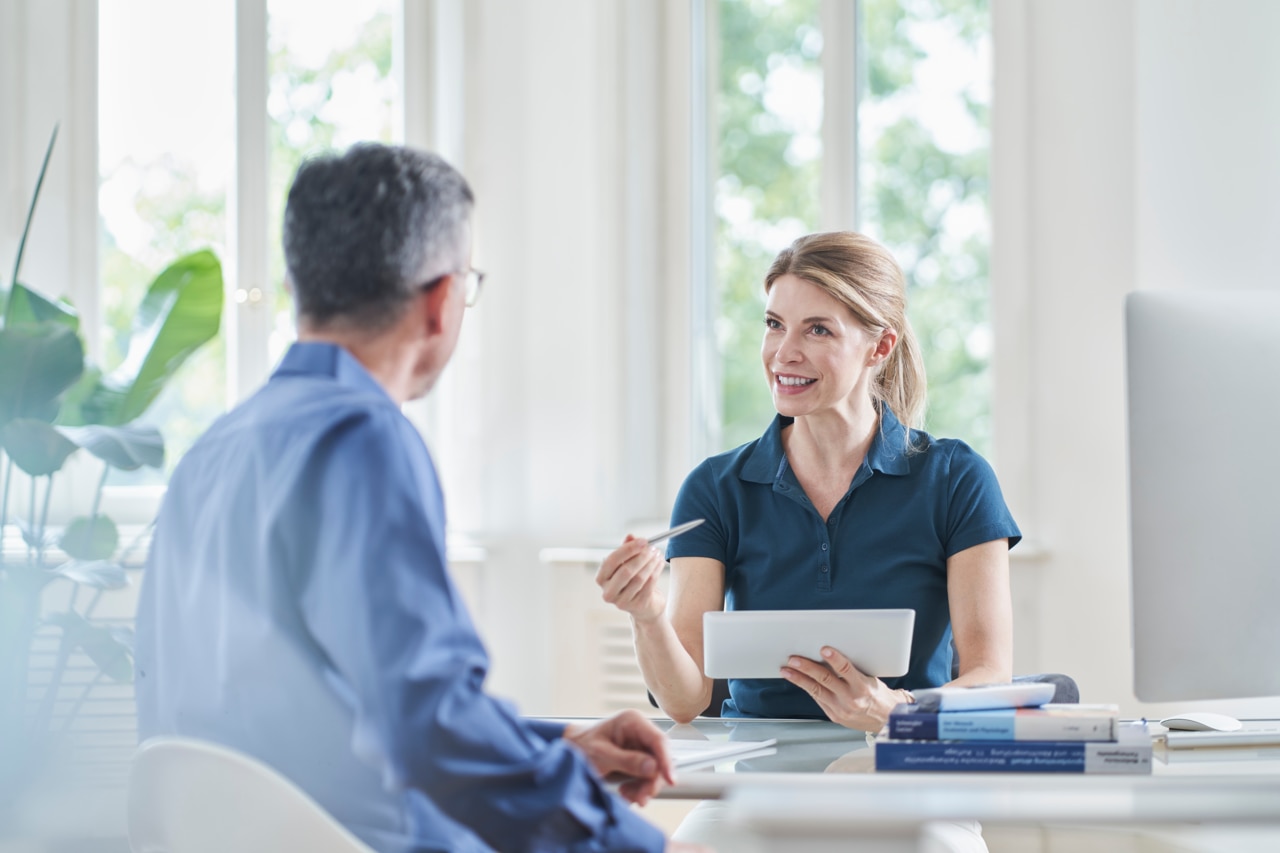 Smiling female doctor gesturing and explaining patient in medical practice