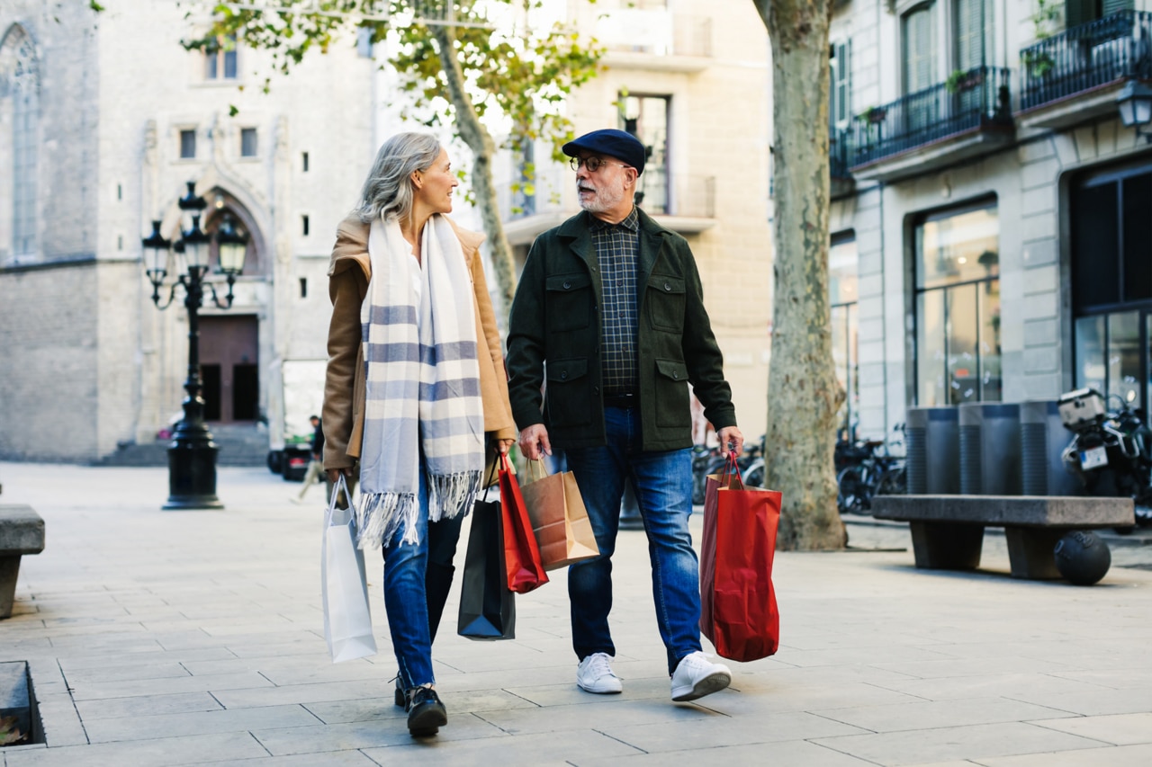 Pareja de ancianos con bolsas de la compra caminando por la calle en invierno.