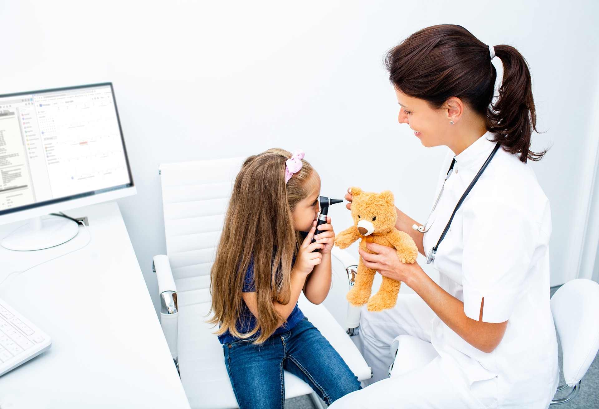little girl looking through the otoscope on the toy's ear. Pediatrician communicates with the child. Kid ear check-up; Shutterstock ID 1805522785; purchase_order: -; job: -; client: -; other: -