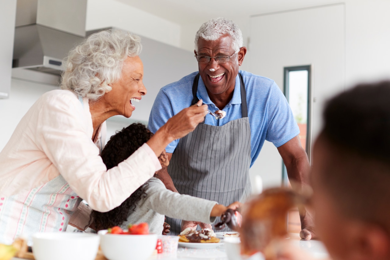 Elderly man and woman in kitchen making breakfast with children
