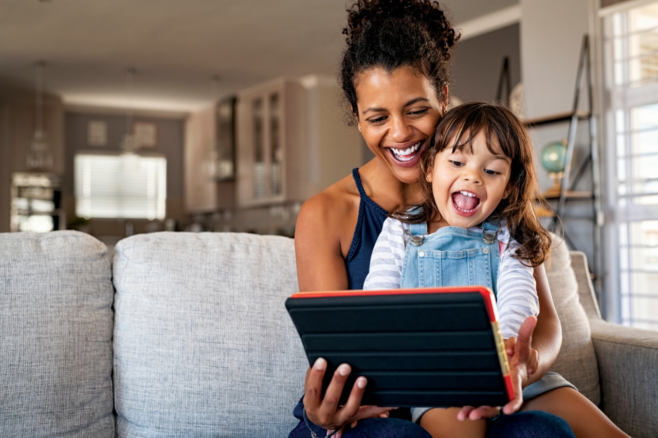 Woman with girl reading from tablet