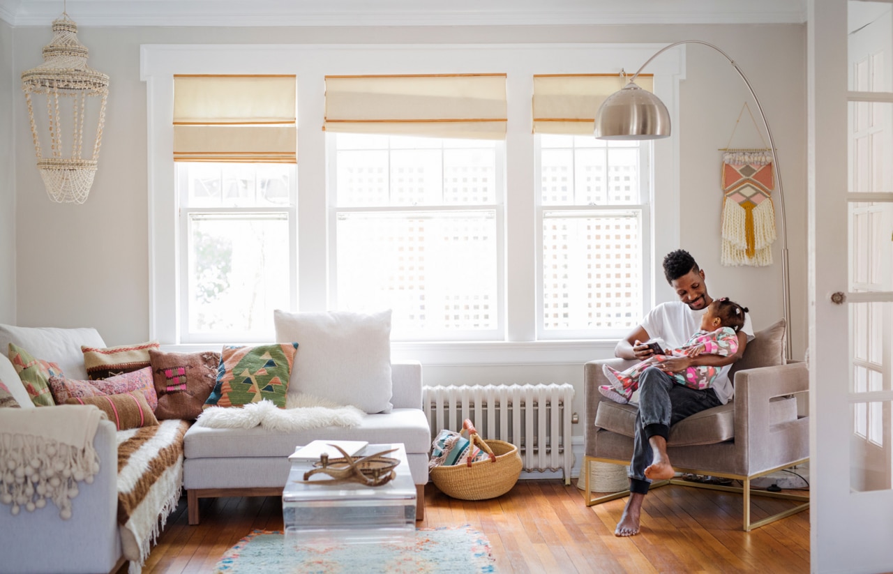 Father holding daughter and playing on a tablet - domestic scene in a living room.