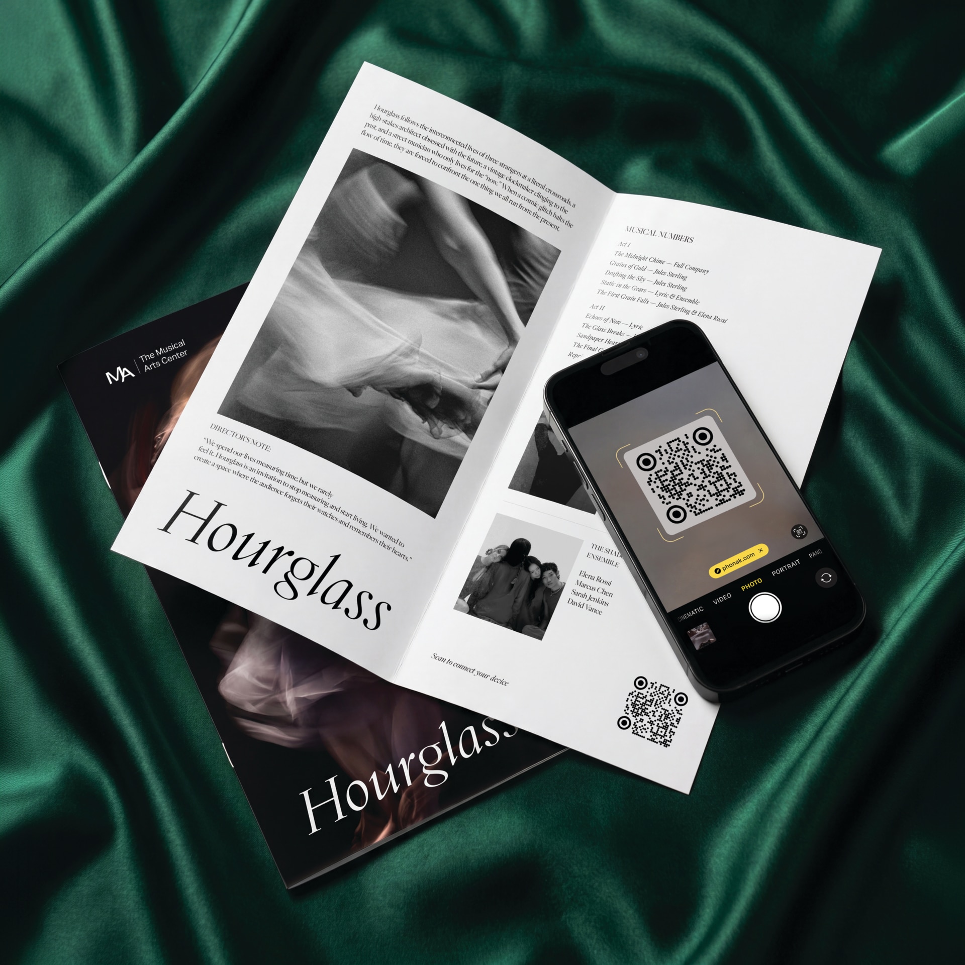 Two Hourglass magazines on dark green velvet fabric; an open two-page spread with grayscale photos sits beside a smartphone displaying a QR code.