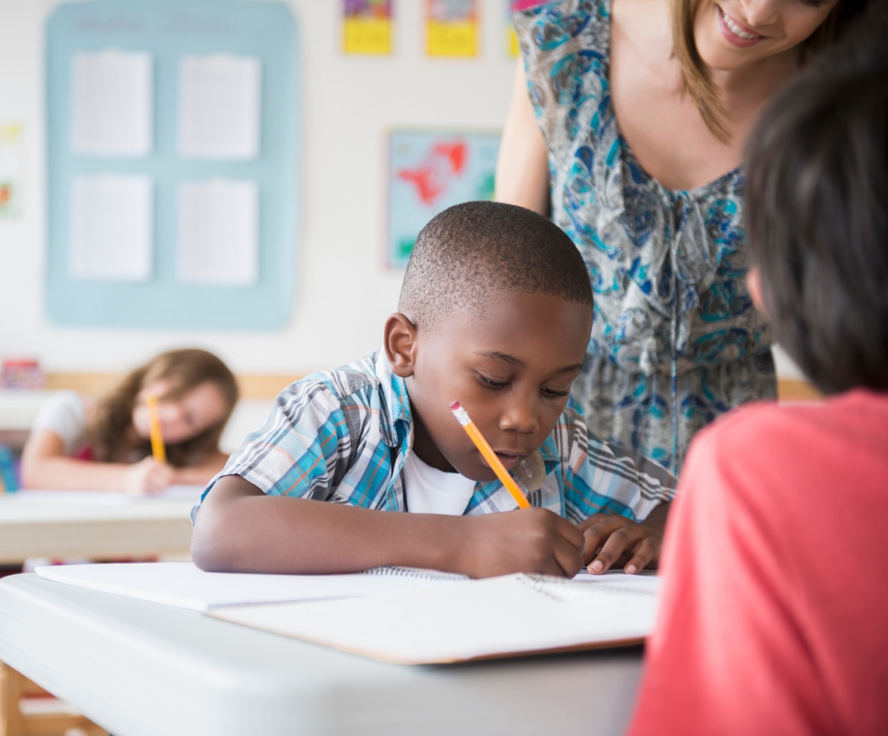 Children and female teacher in a classroom. Children (8-9) with female teacher learning in classroom